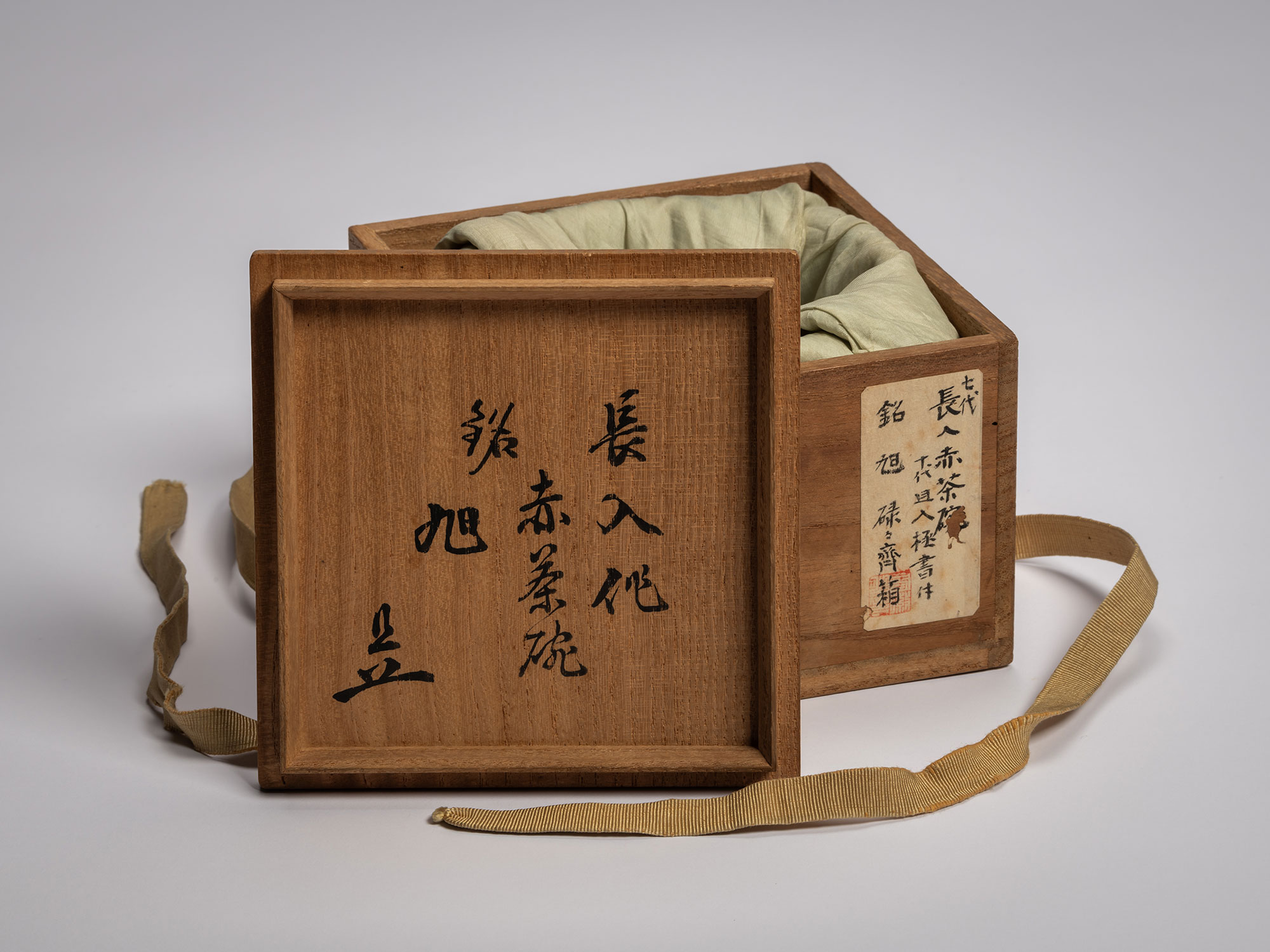 Surface of a dark-toned wooden interior lid for the Asahi tea bowl, featuring three columns of...