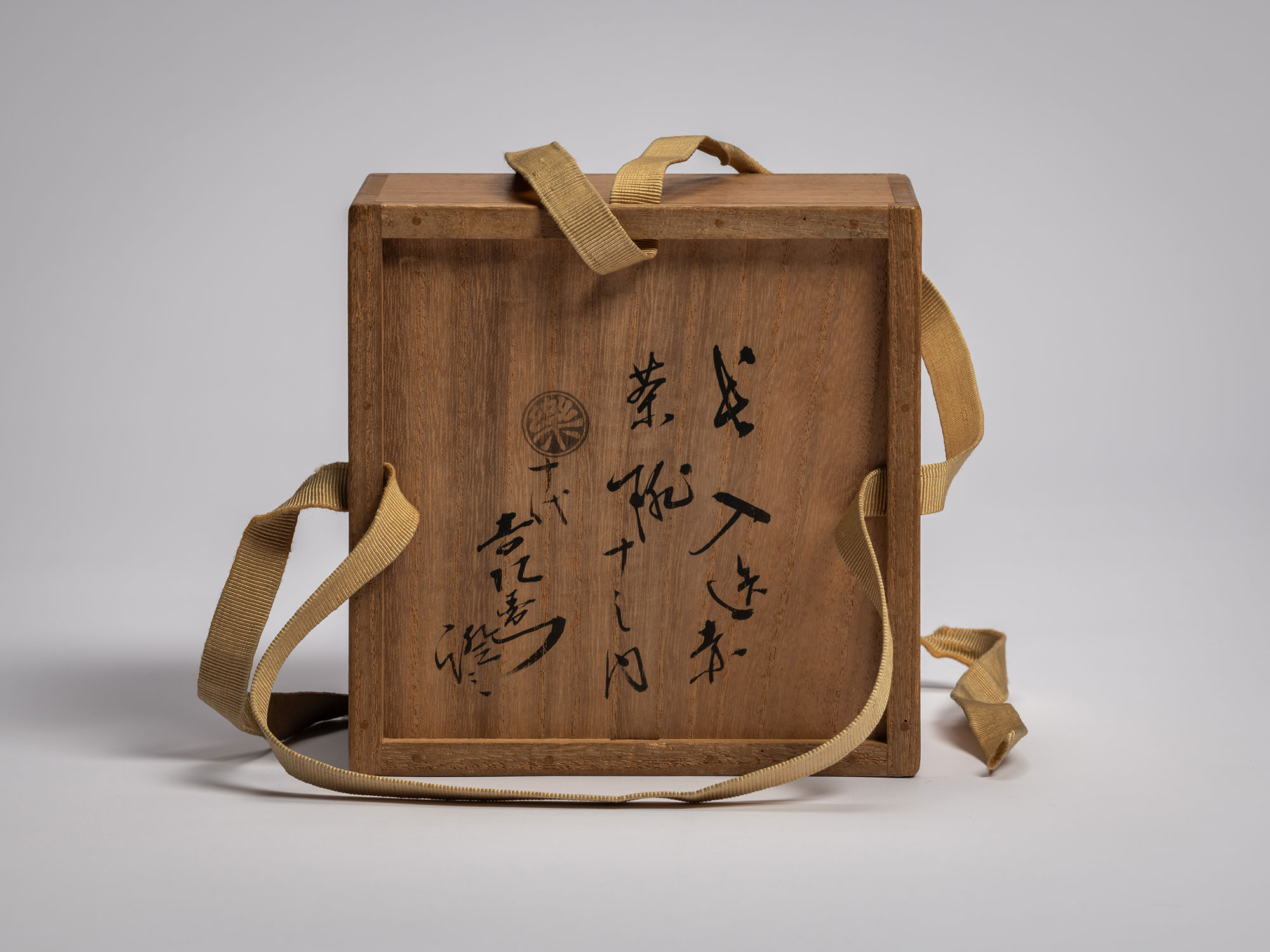 Underside of a dark wood interior tomobako for the Asahi tea bowl, featuring three columns of vertical...