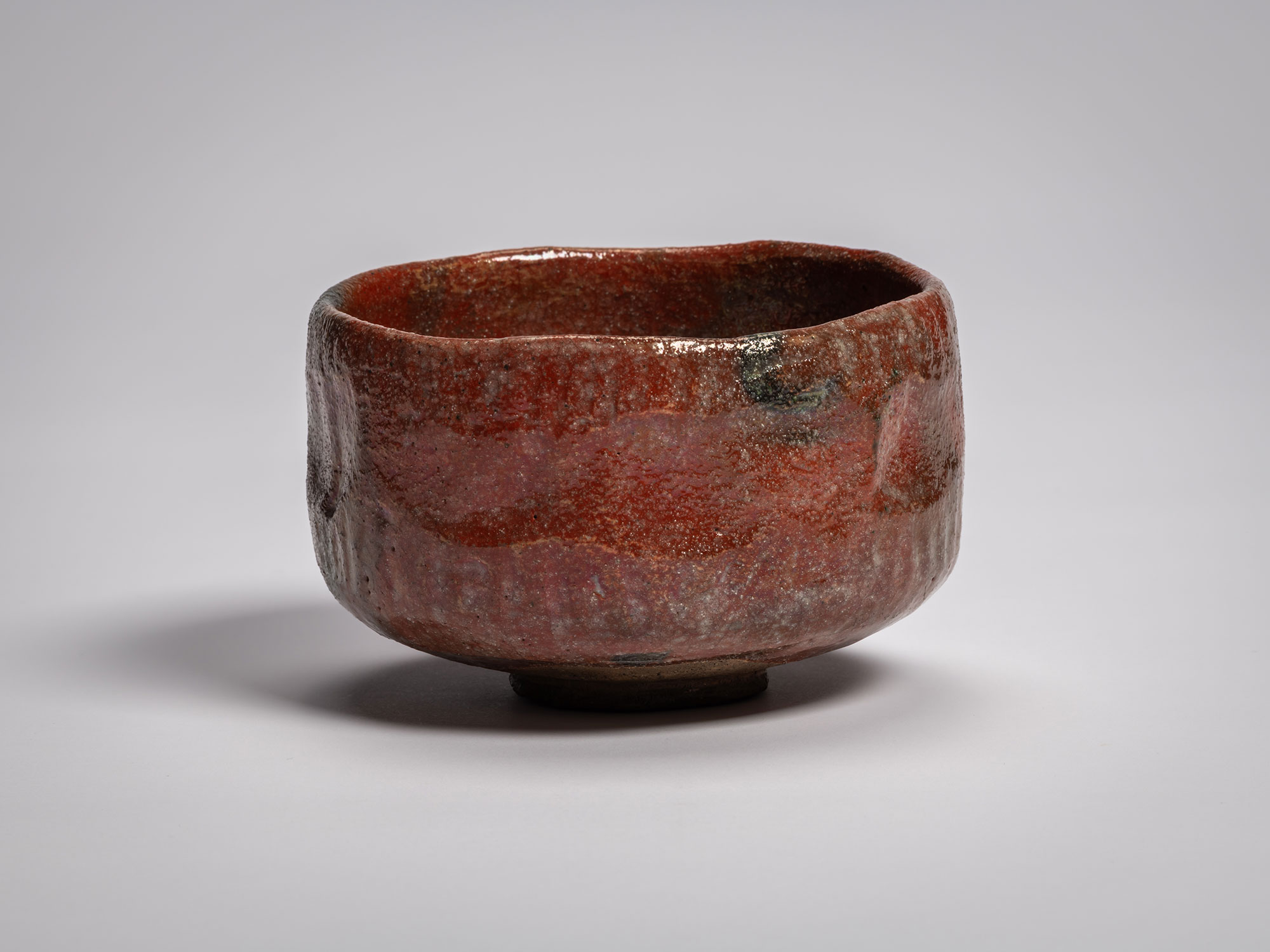 Profile view of the authentic red Raku tea bowl named Asahi (Morning Sun), handcrafted by Raku...