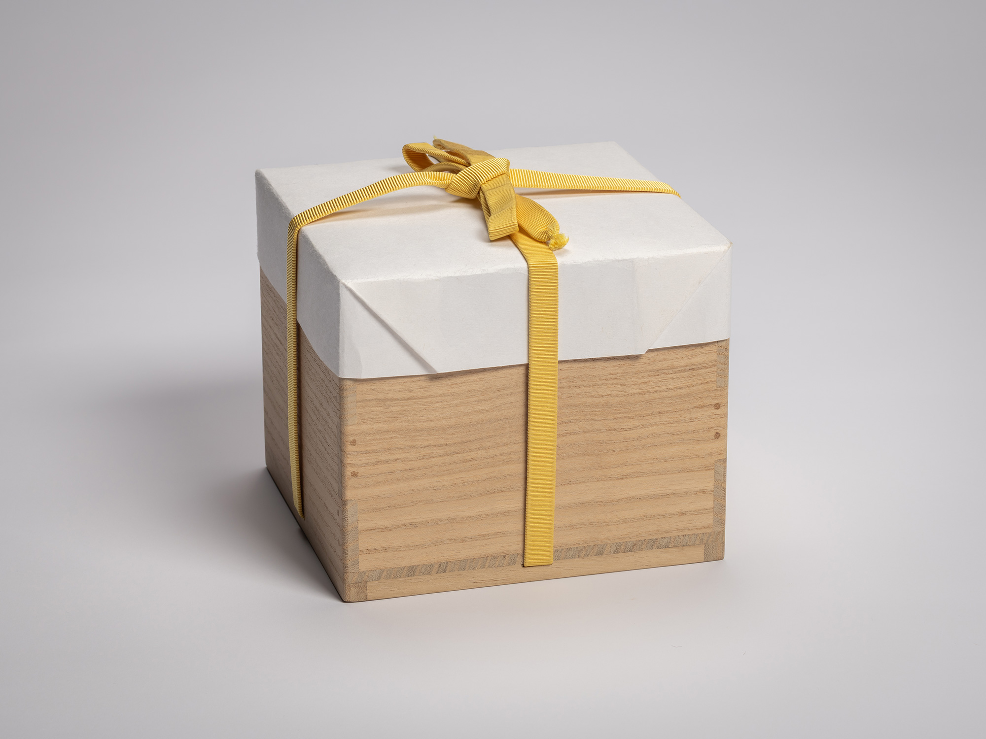 Closed wooden tomobako for a Black Raku tea bowl, wrapped in white washi paper and secured with...