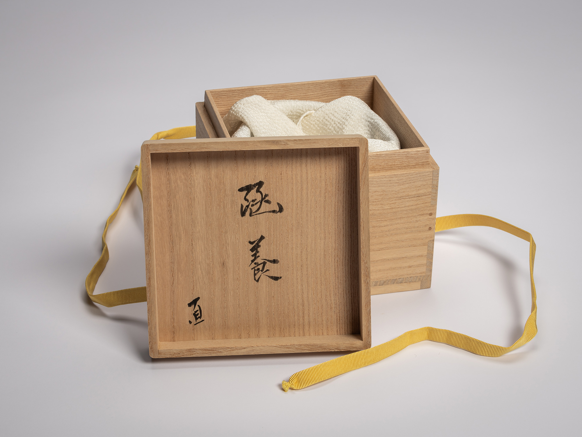Interior lid of a wooden tomobako for a Black Raku tea bowl, inscribed in black ink with vertical...