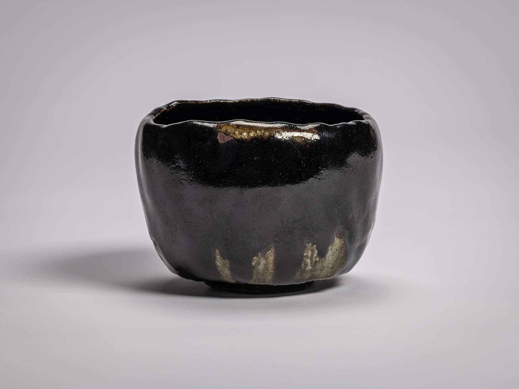 Black Raku tea bowl by Raku XV with a softly undulating rim, deep glossy black glaze, and subtle...