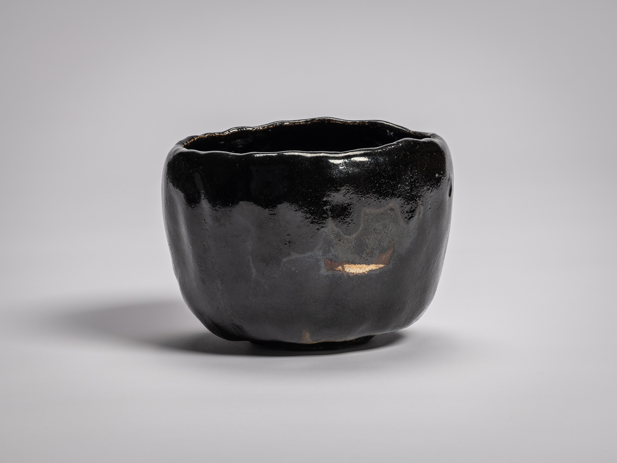 Black Raku tea bowl by Raku XV with a softly undulating rim, deep glossy black glaze, and subtle...