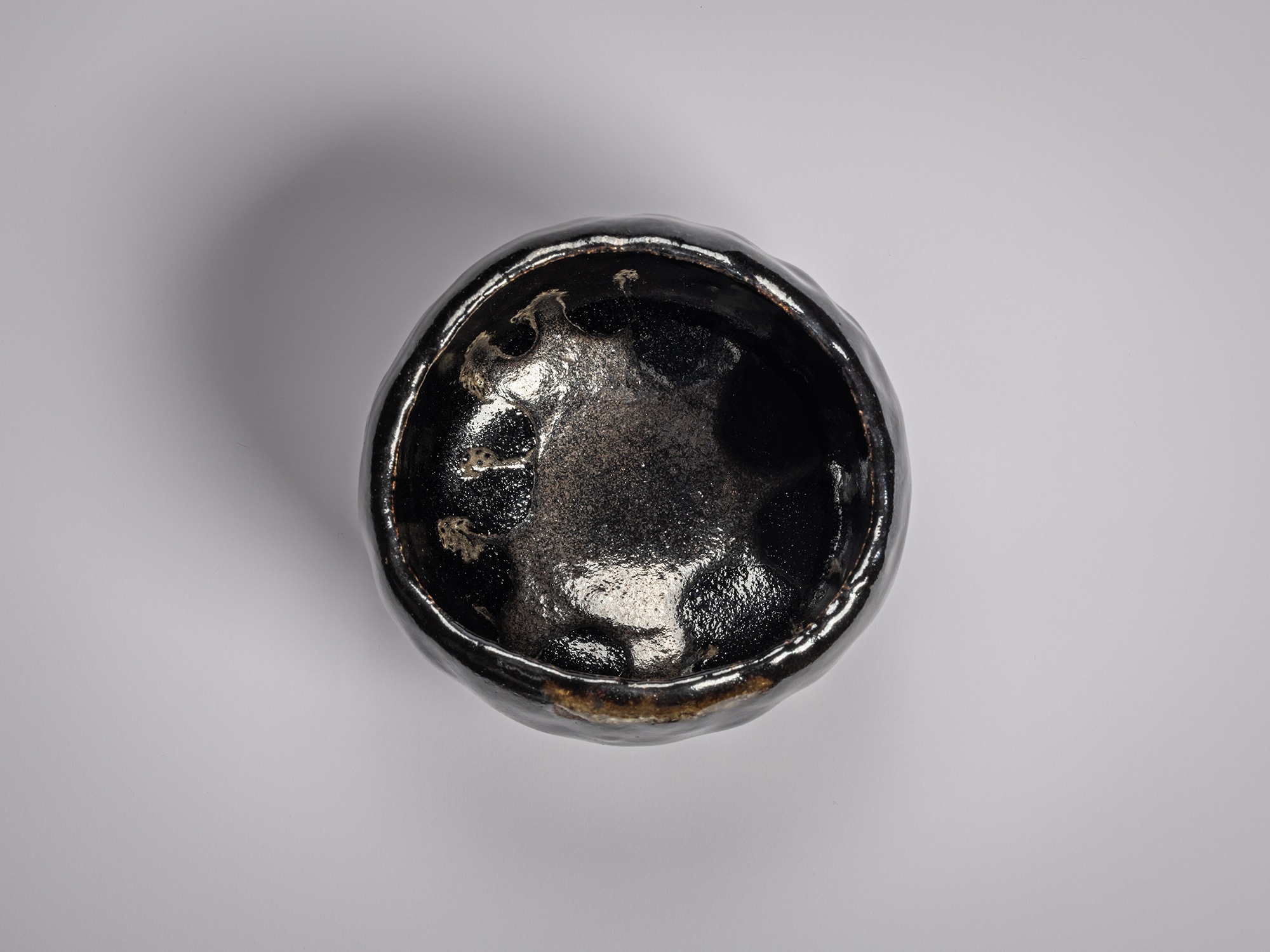 Interior view of a Black Raku tea bowl by Raku XV, showing a glossy black glaze with pooled highlights,...