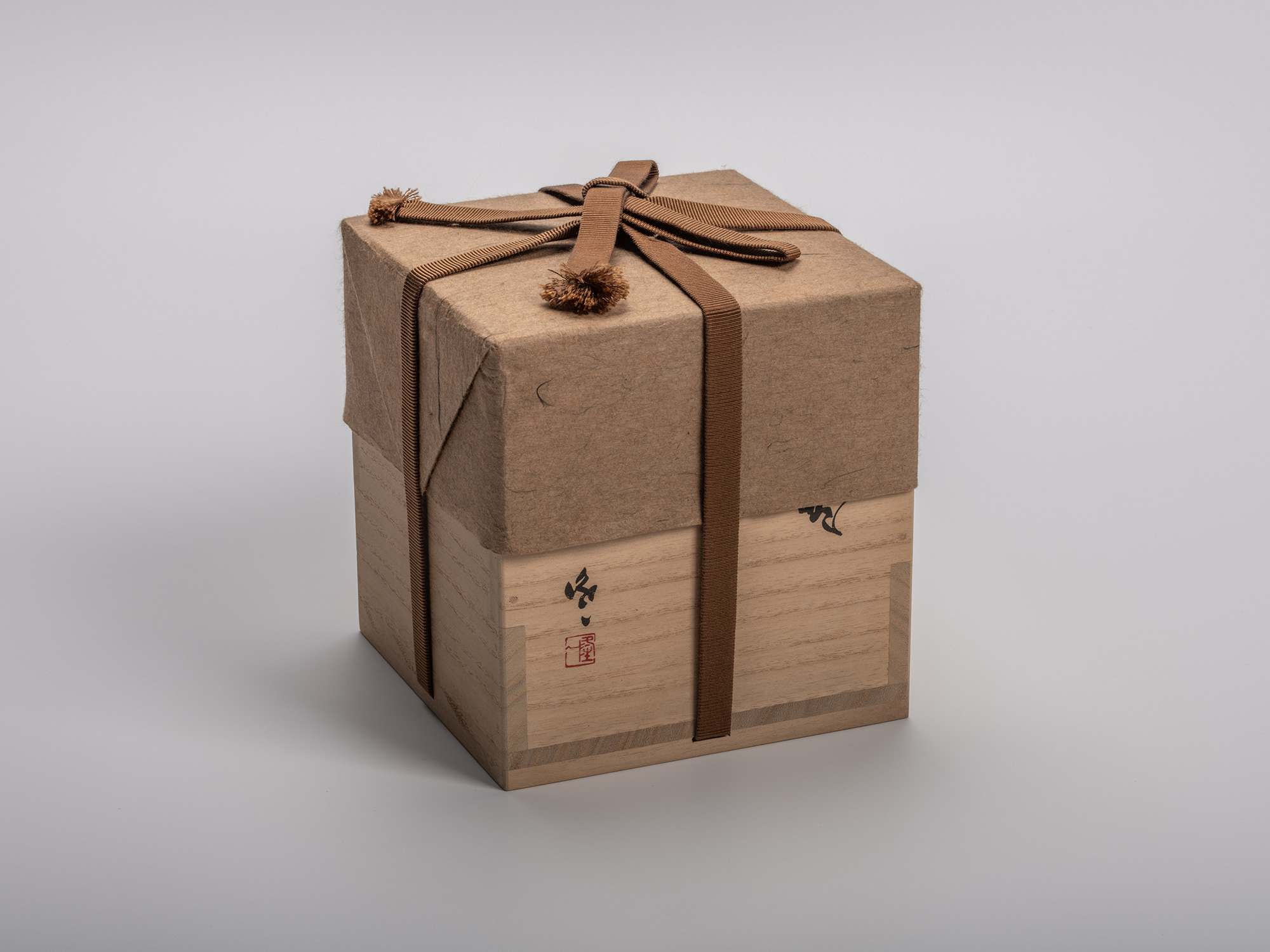 Wooden tomobako (artist box) for a black tea bowl by Kakurezaki Ryūichi, wrapped with a brown silk...
