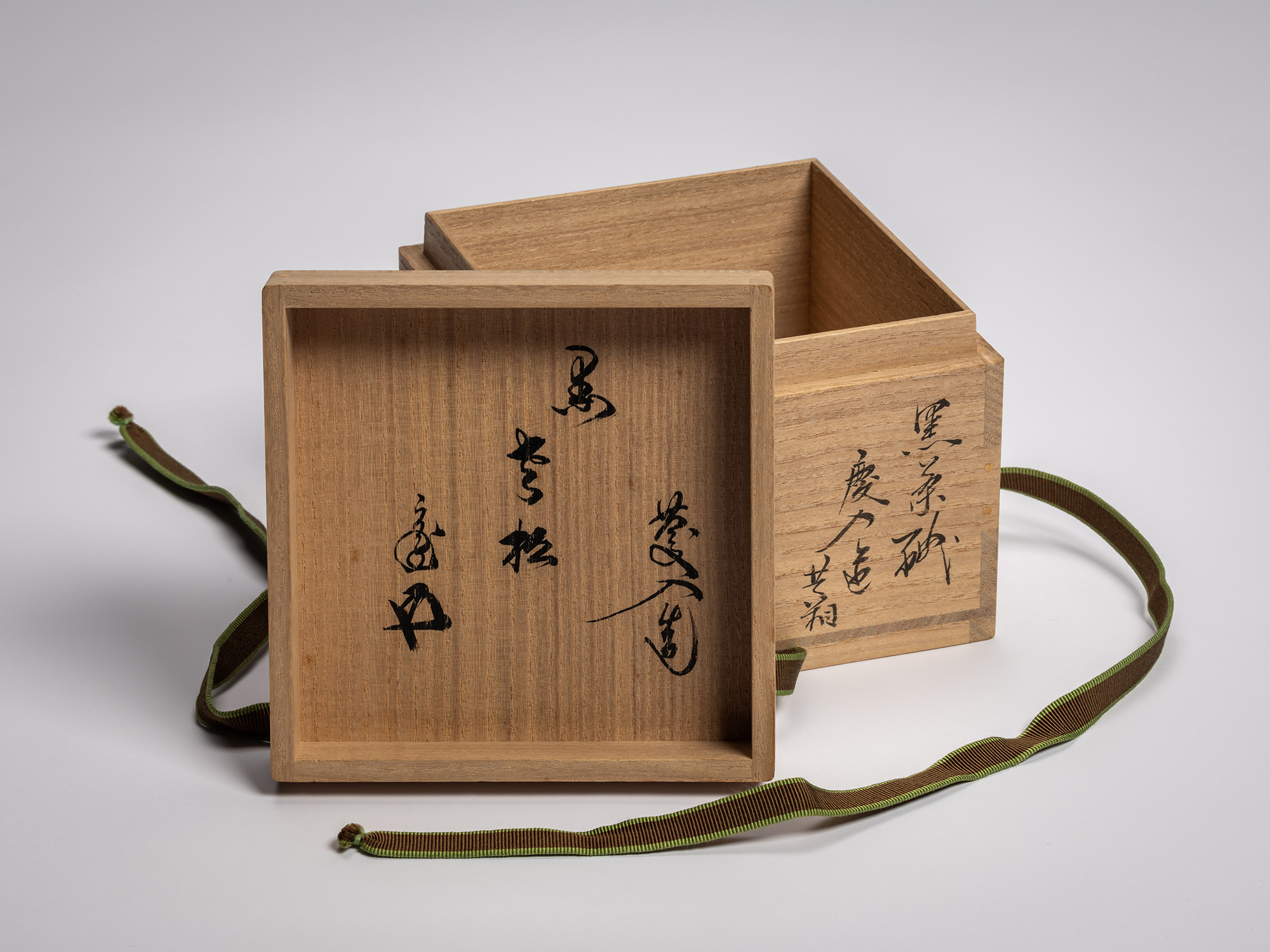 A close-up view of the interior side of a paulownia wood lid for a Black Raku tea bowl, featuring...