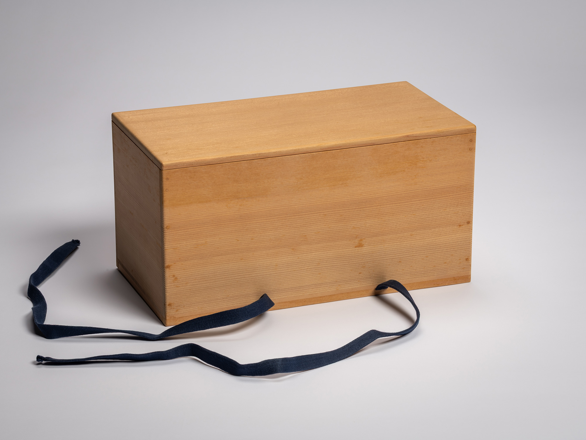 Exterior view of a rectangular, light-toned paulownia wood storage box (tomobako) for a Japanese...