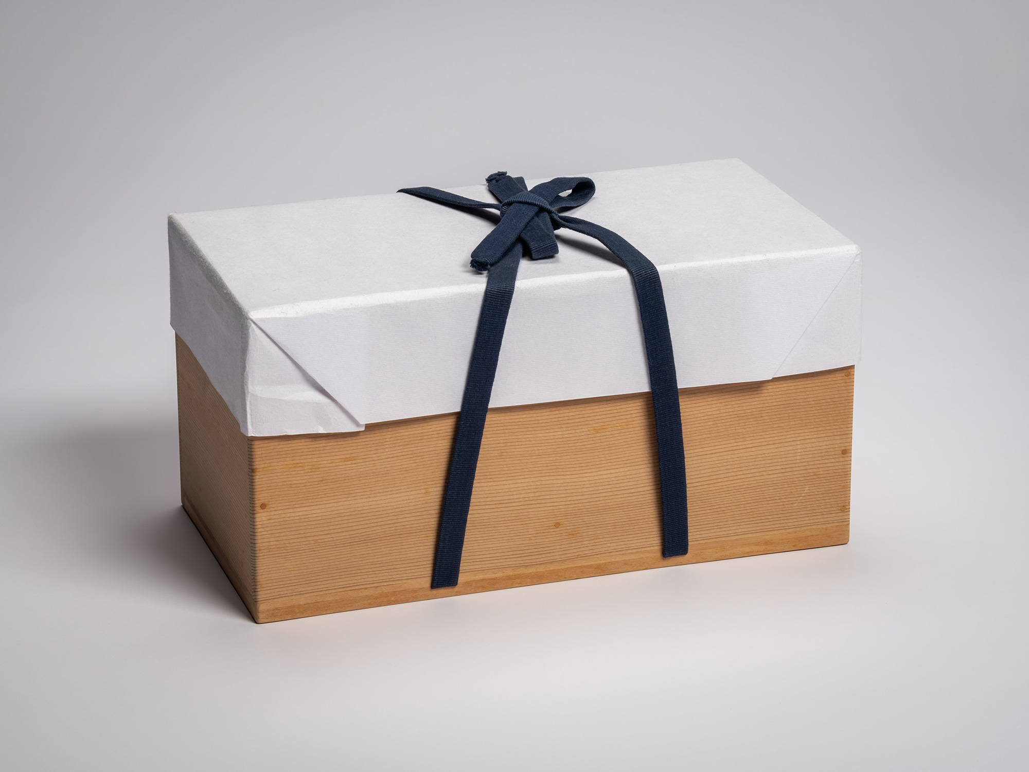 Exterior view of a rectangular, light-toned paulownia wood storage box (tomobako) for a Japanese...