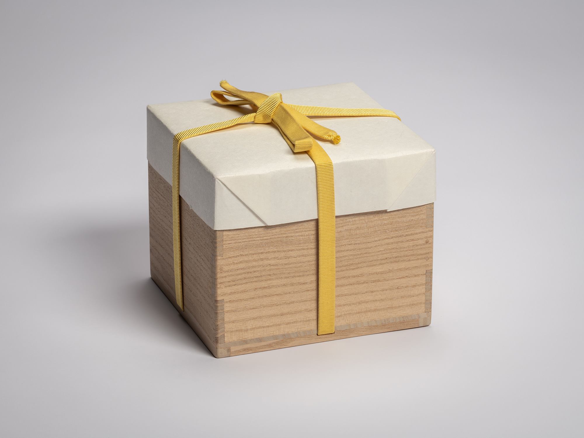 Wooden artist box containing the tea bowl by Raku XV (Jikinyū), tied with a yellow cord and topped...