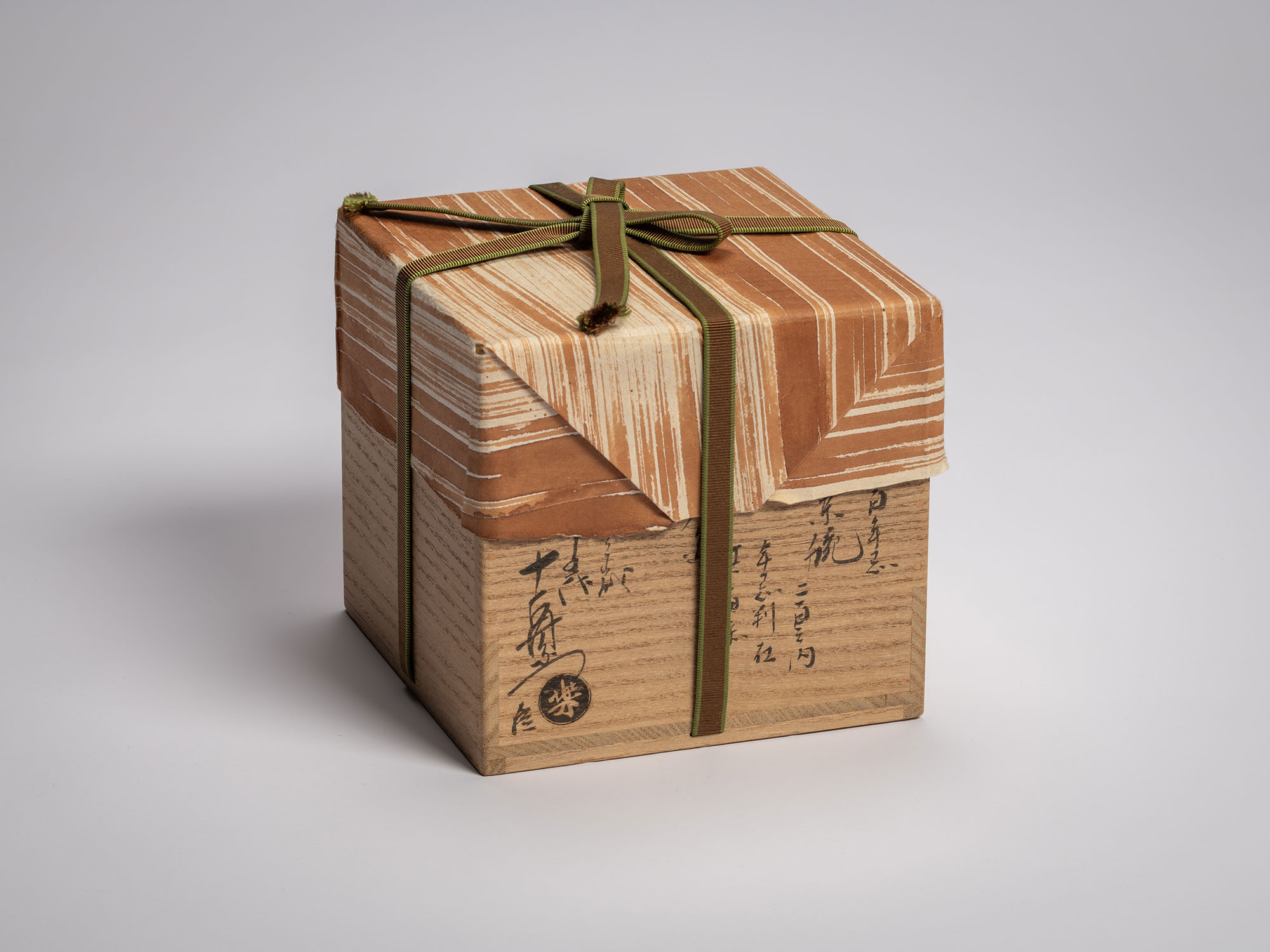 Wooden storage box for the tea bowl Daiyūhō by Raku IX, wrapped with diagonally folded brown washi...