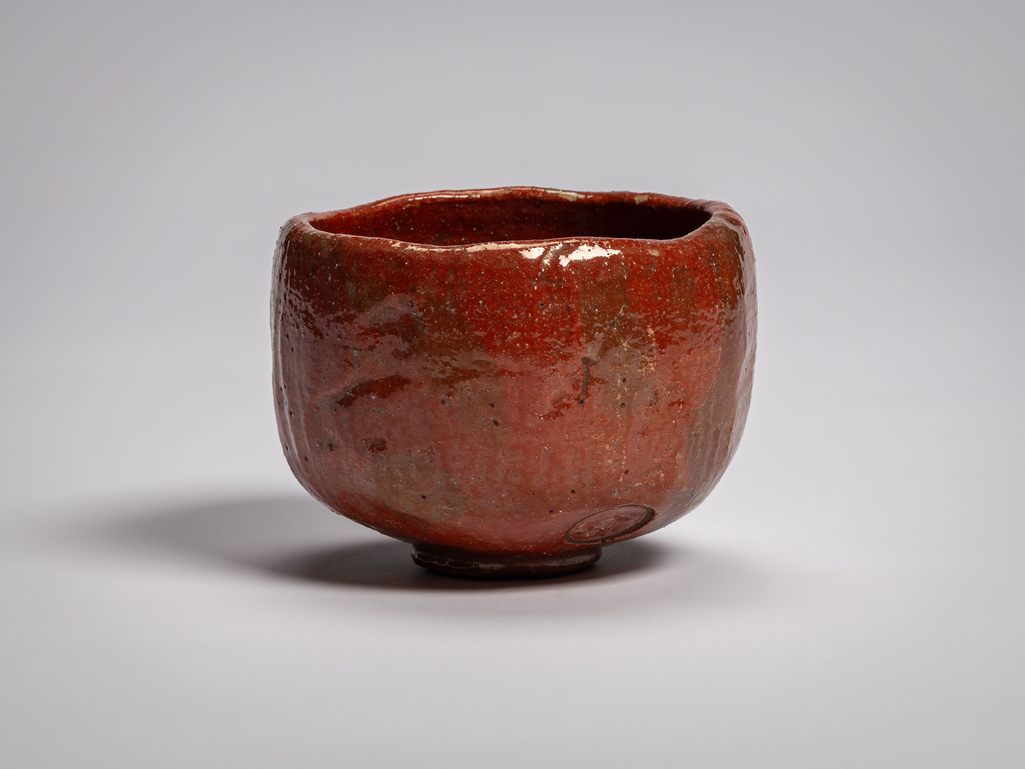 Red Raku tea bowl Daiyūhō (Great-Peak) Raku IX, with a softly rounded form, irregular rim, and...