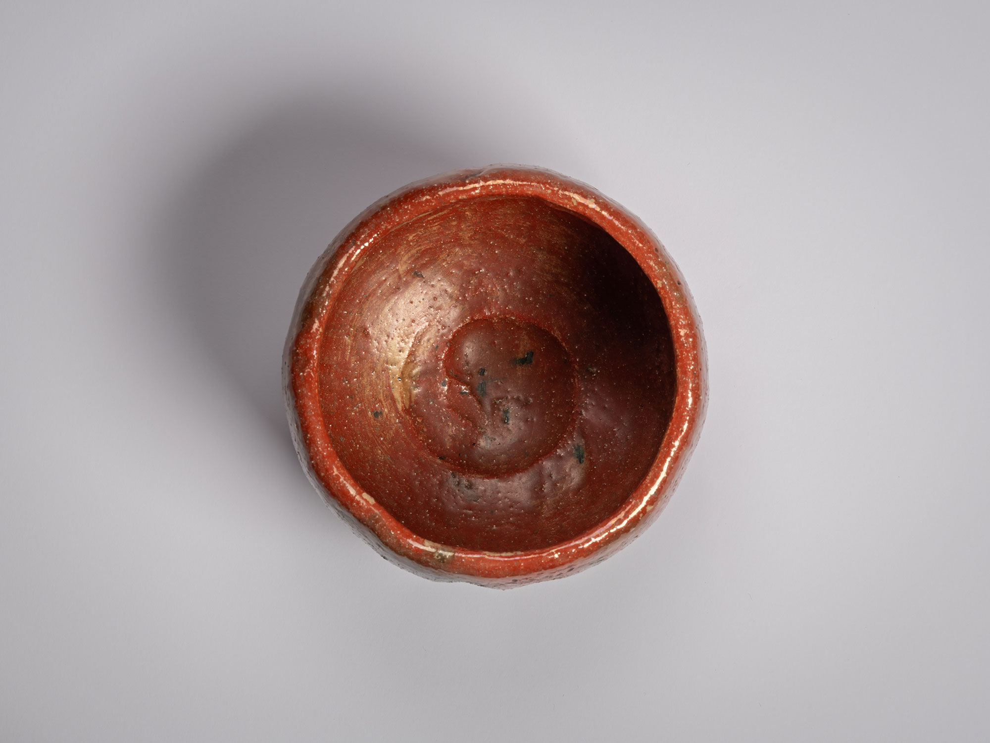 Top-down view of the interior of an authentic red Raku tea bowl (chawan) named Daiyūhō, showing...