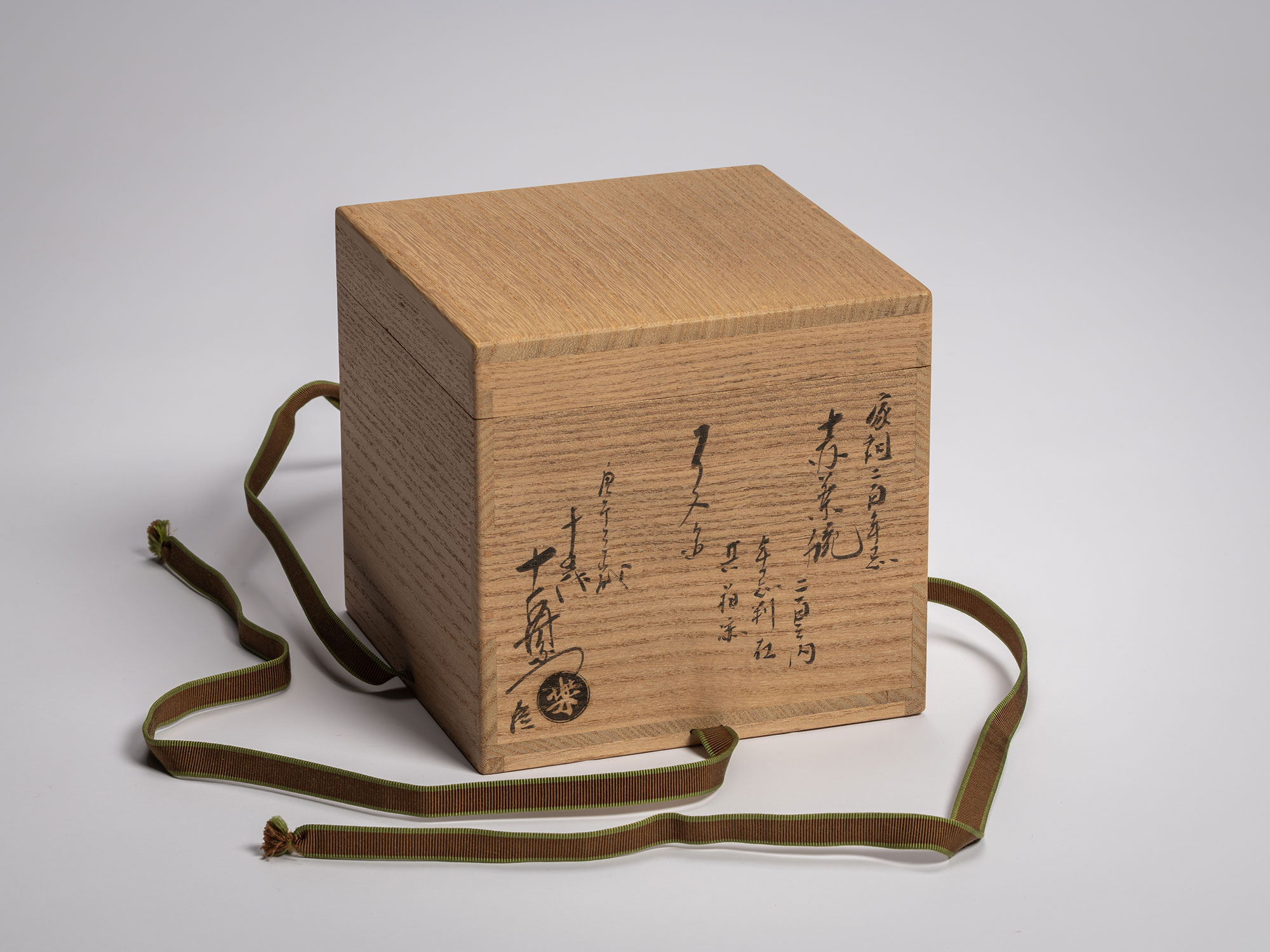 A high-quality Japanese Raku tea bowl wood box (tomobako) featuring calligraphy by Raku XV authenticating...
