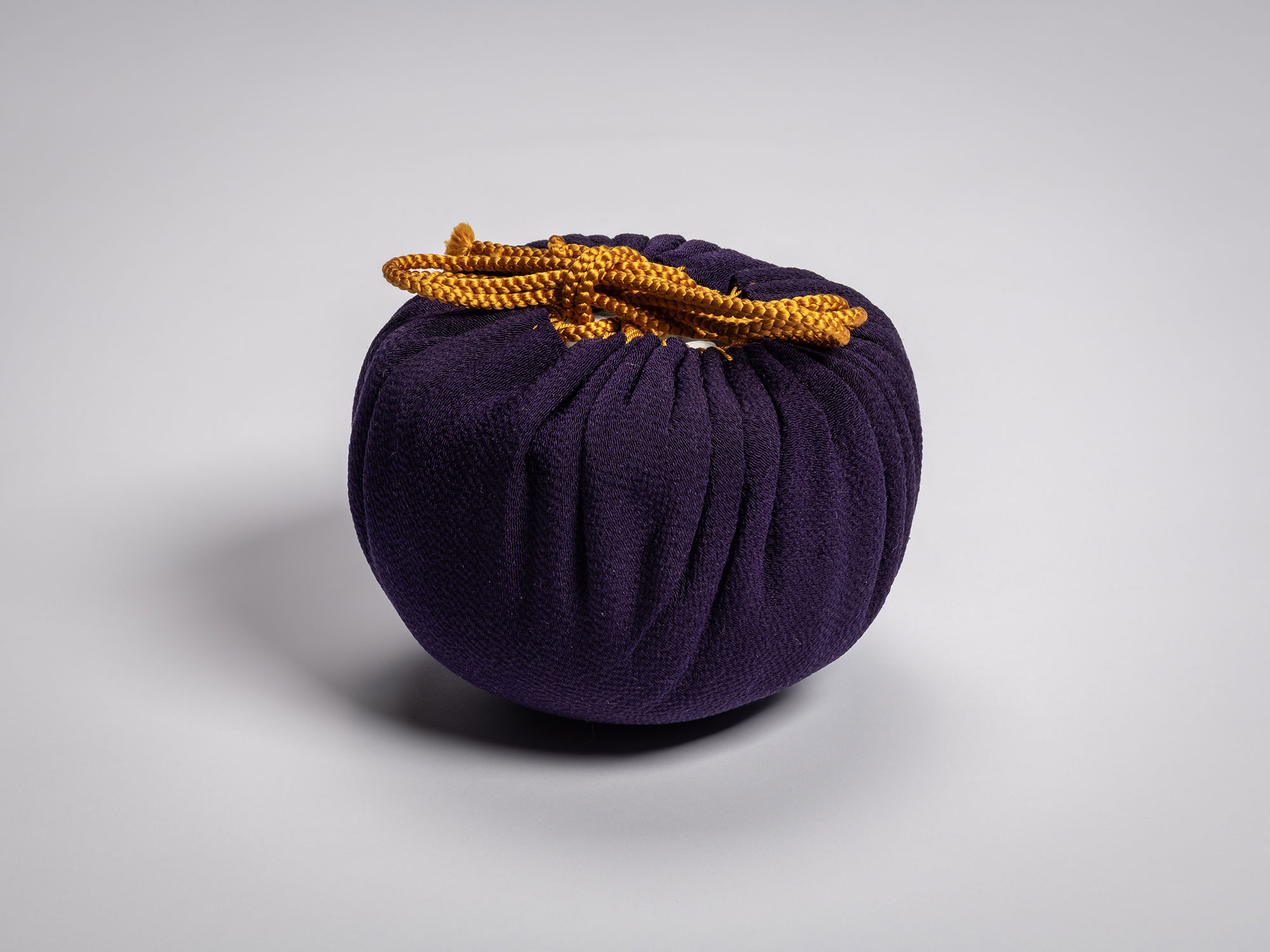 The tea bowl Daiyūhō (Great Peak) by Raku IX fully wrapped in a deep purple silk cloth (fukusa),...