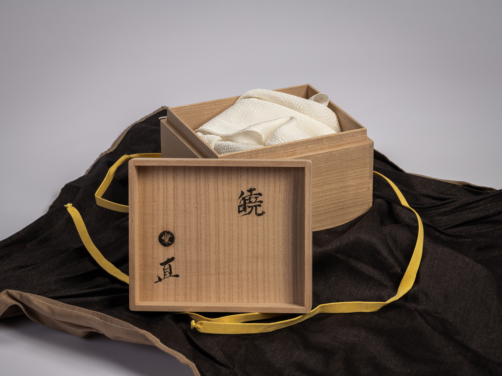 Interior of the wooden artist box for the tea bowl Gyō by Raku XV (Jikinyū), showing folded silk...
