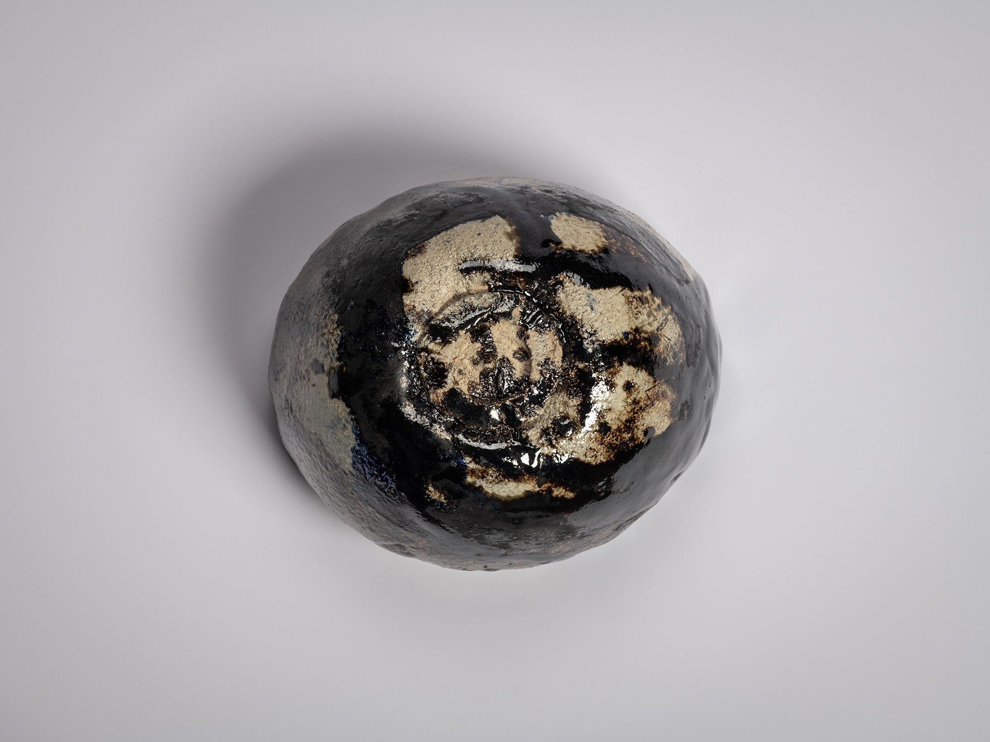 Foot (kōdai) of a Black Raku tea bowl showing a hand-carved circular foot ring with exposed buff...