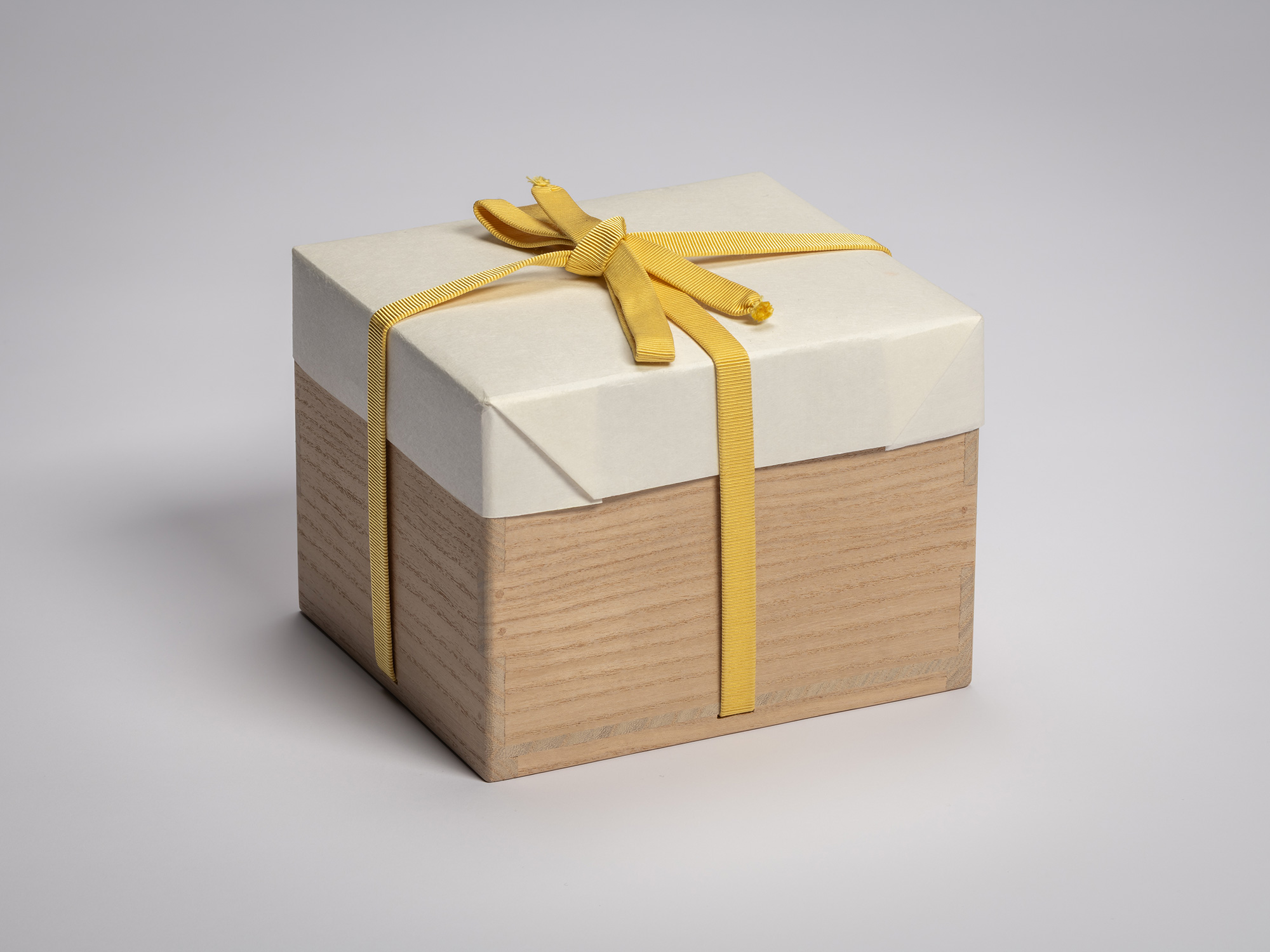 Wooden artist box containing the tea bowl Hatō by Raku XV (Jikinyū), tied with a yellow cord and...