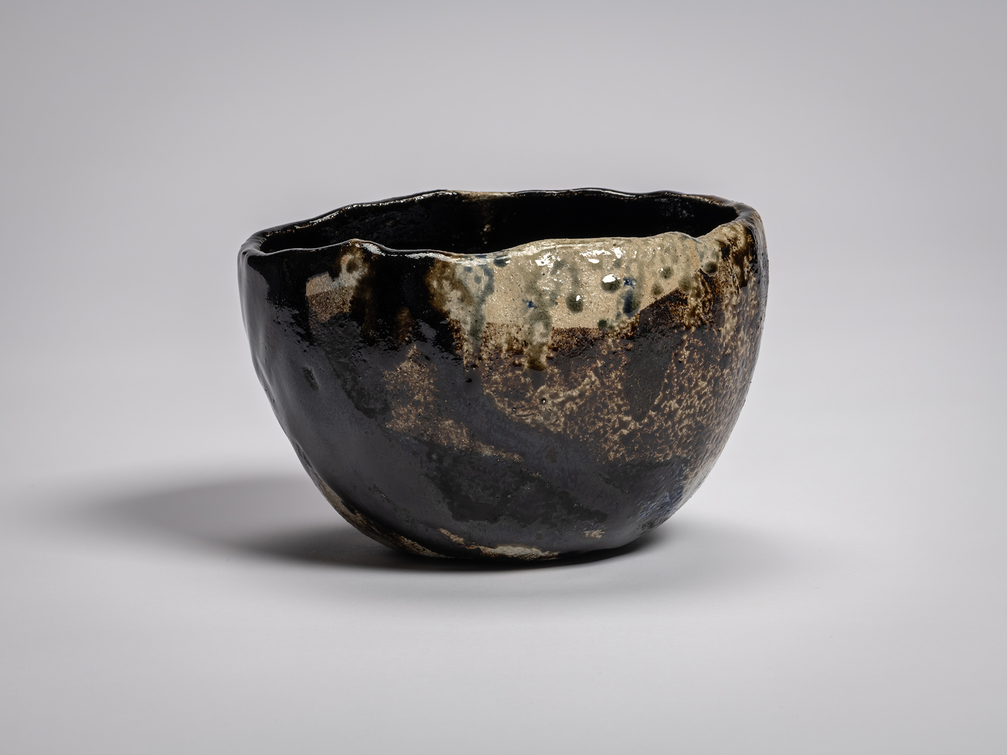 Black Raku tea bowl by Raku XV titled Hatō (Great Wave in Ocean), featuring an irregular, hand-formed...