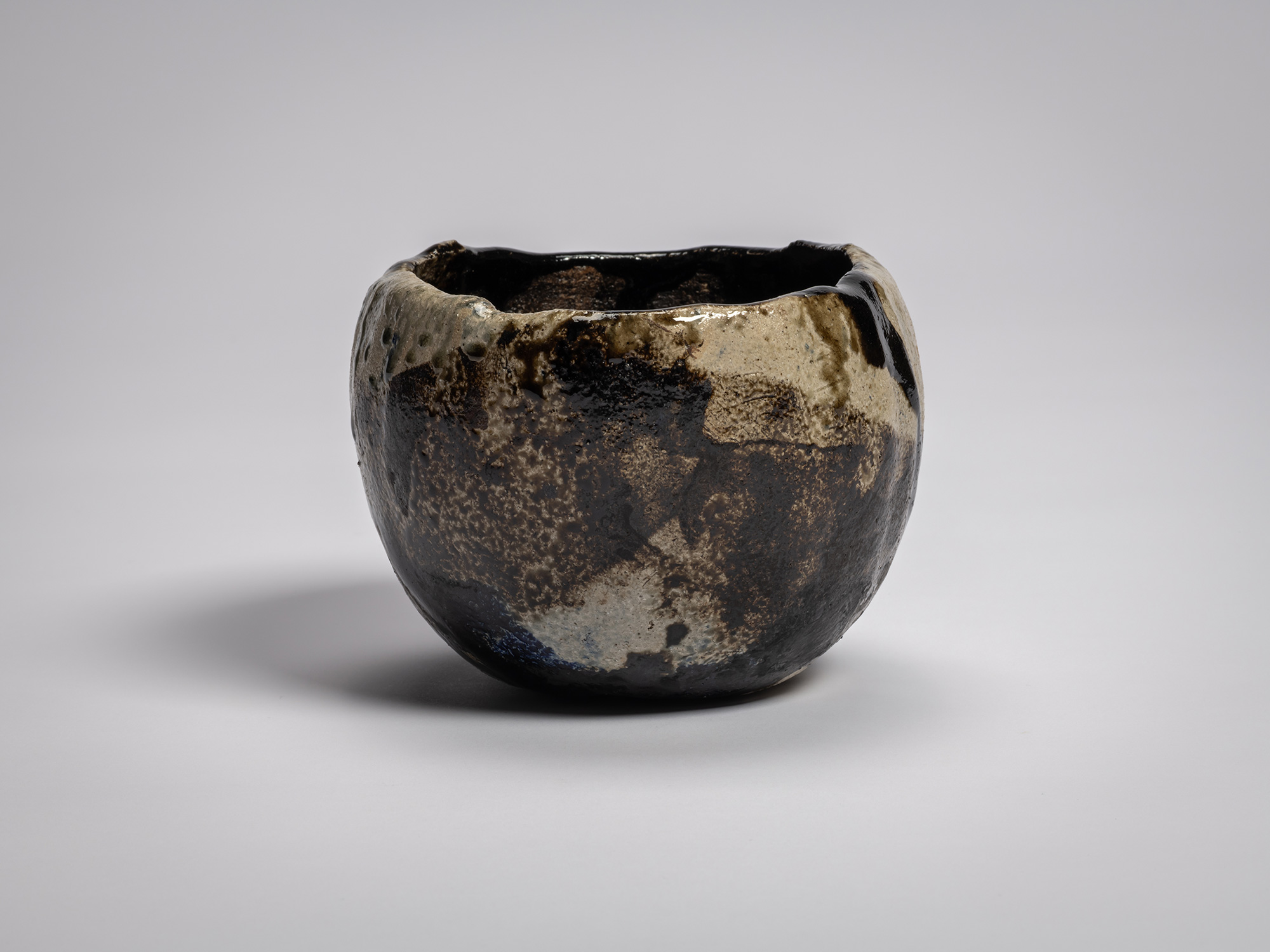 Side profile of black raku tea bowl by Raku XV titled Hatō (Great Wave in Ocean), featuring an...