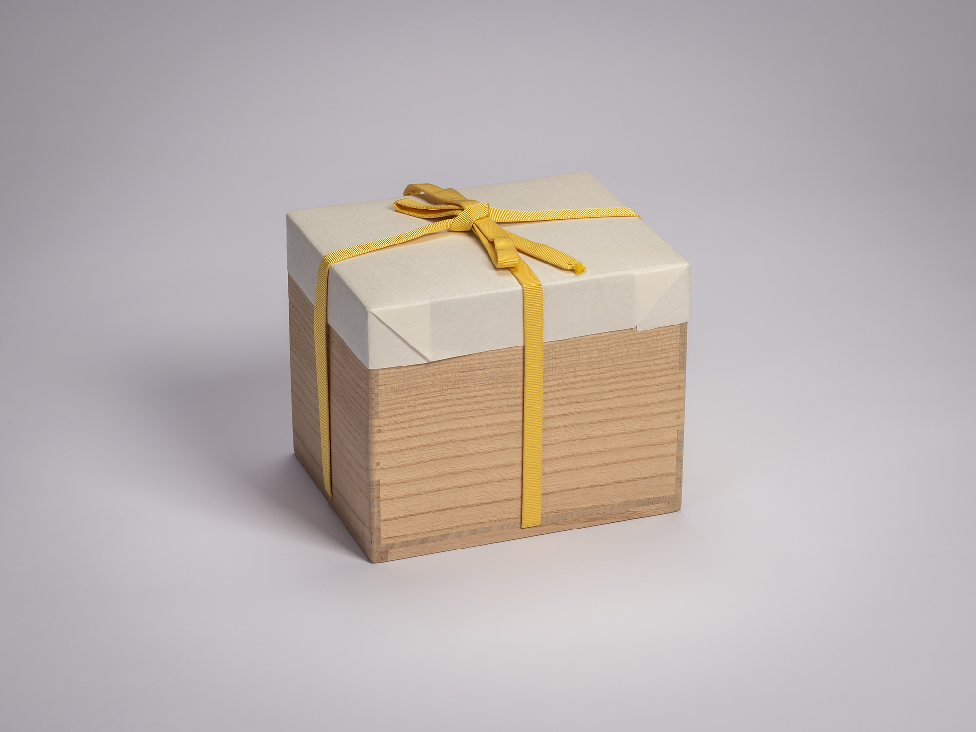 Wooden artist box containing the tea bowl Hyō by Raku XV (Jikinyū), tied with a yellow cord and...
