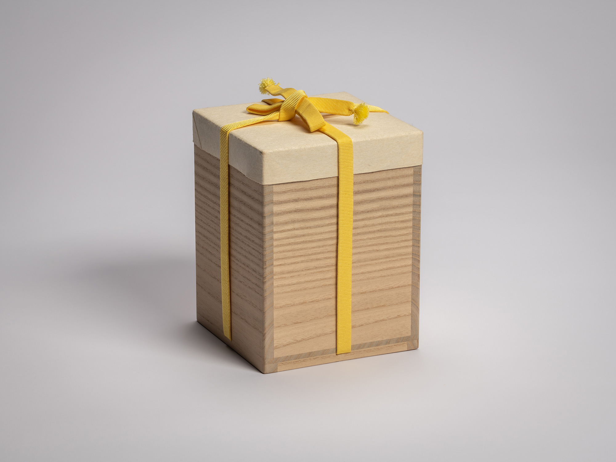 Light wood kiri exterior storage box secured with a yellow braided cord tied across the lid that...