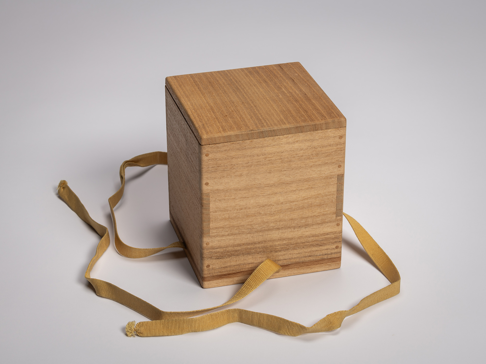Untied kiri wood storage box with paper removed, revealing smooth, uninscribed surfaces and yellow...