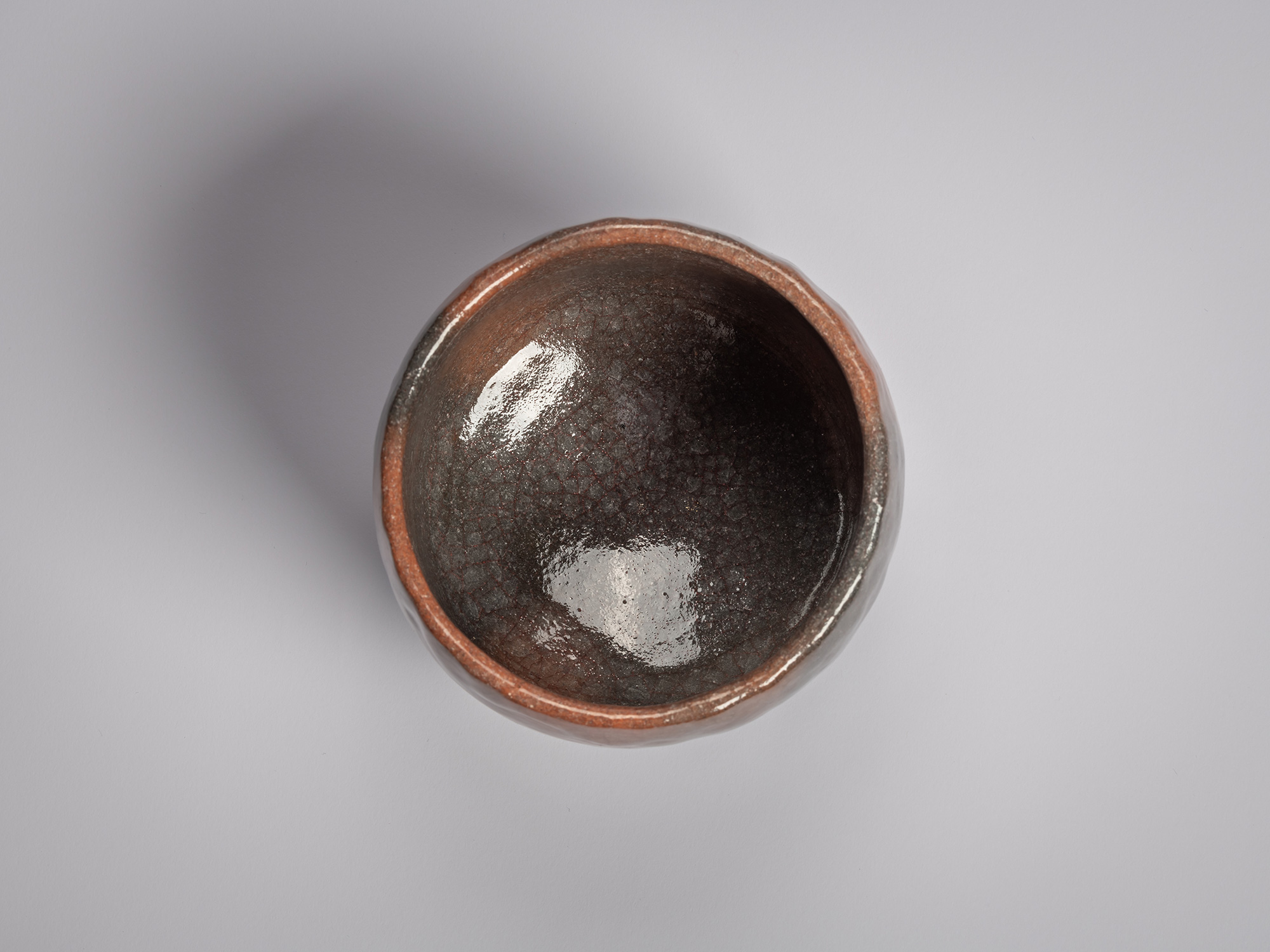 Interior of a Red Raku tea bowl by Raku XVI, showing a dark, lustrous glaze with fine crackle,...