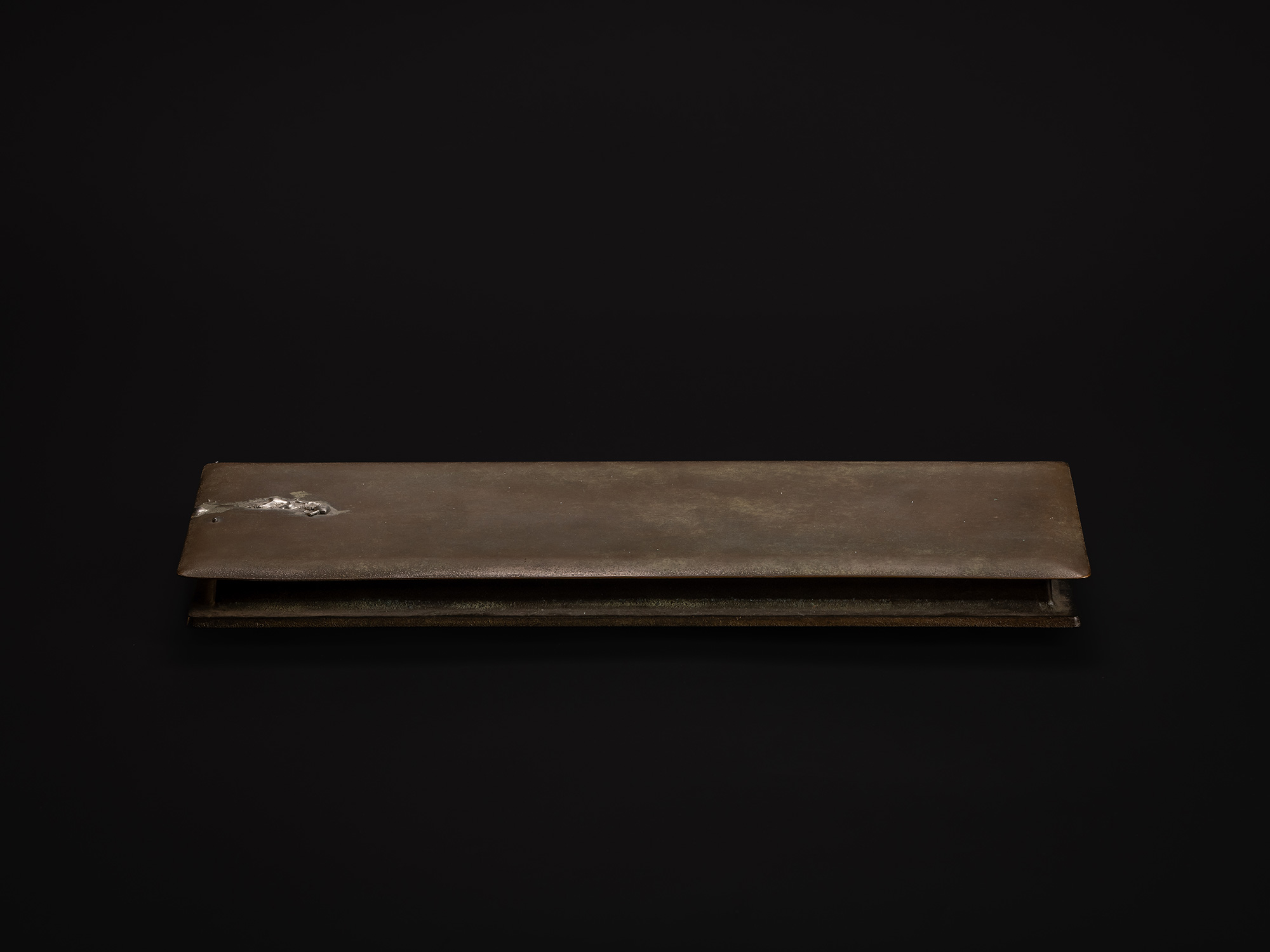 Side view of Sideways Bronze by Koji Hatakeyama, showing a long, low rectangular bronze form with...