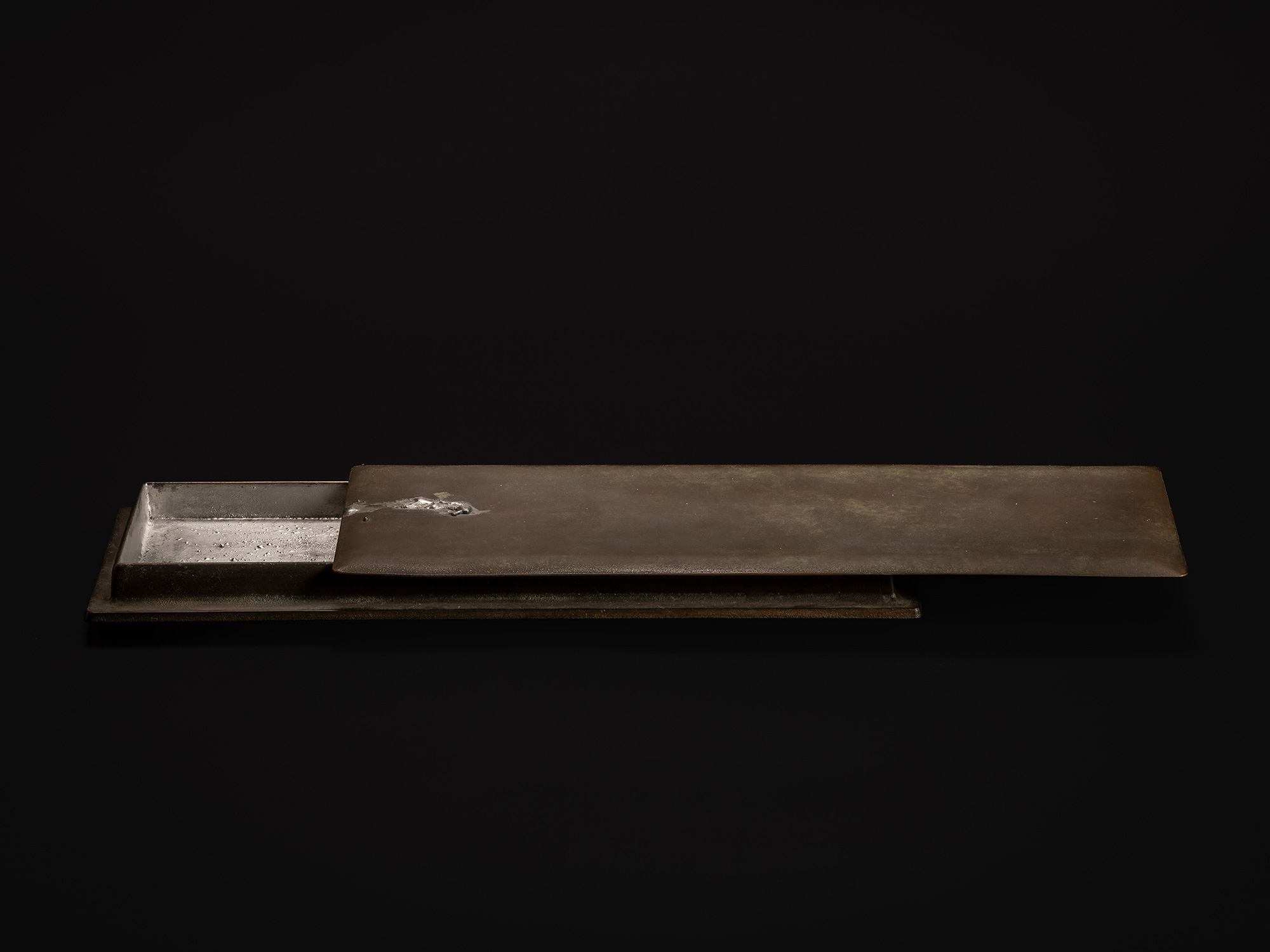 View of Sideways Bronze by Koji Hatakeyama, showing the long bronze lid slid partially open to...