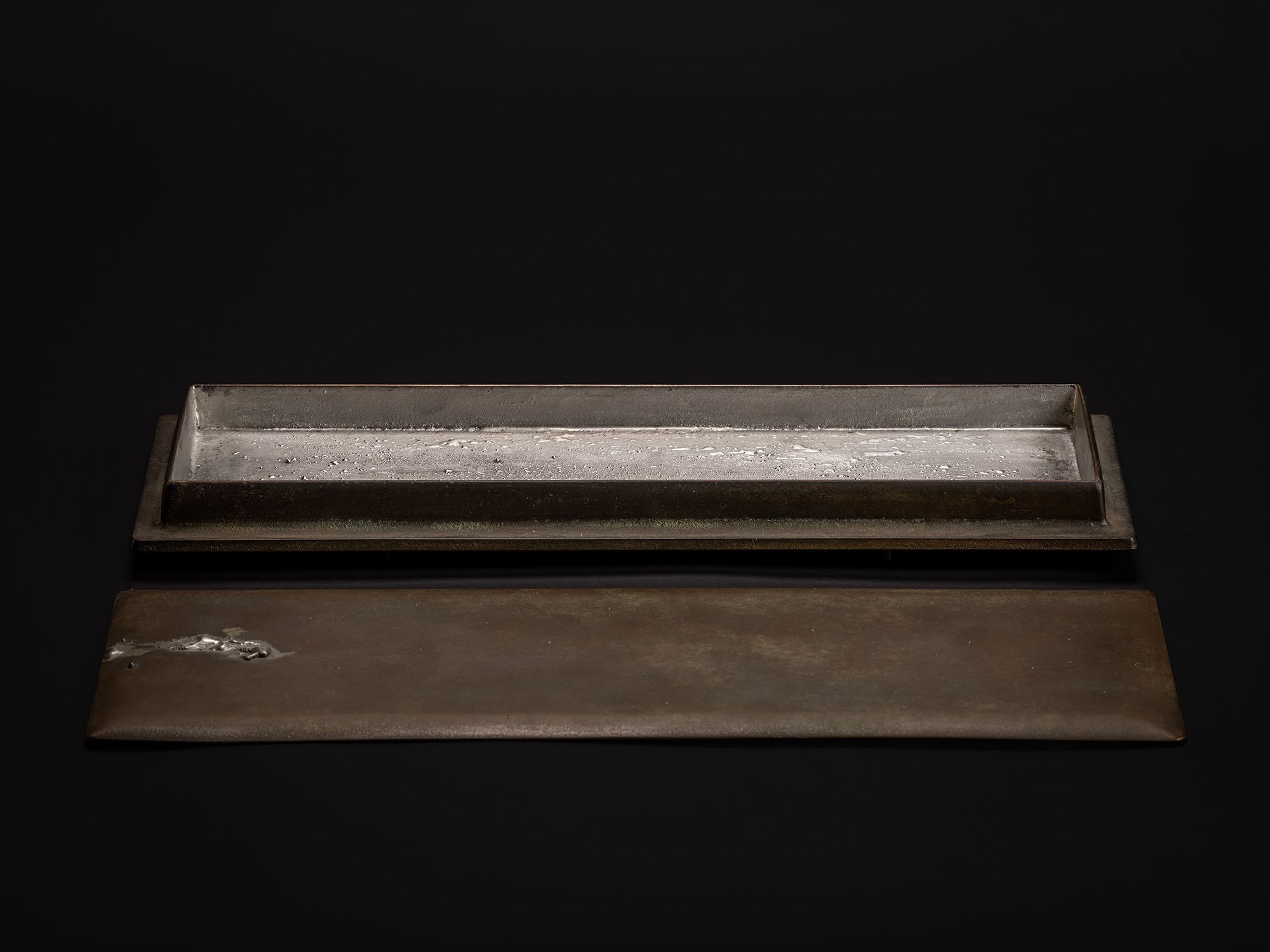 Sideways Bronze by Koji Hatakeyama shown with the lid fully removed and placed in front of the...