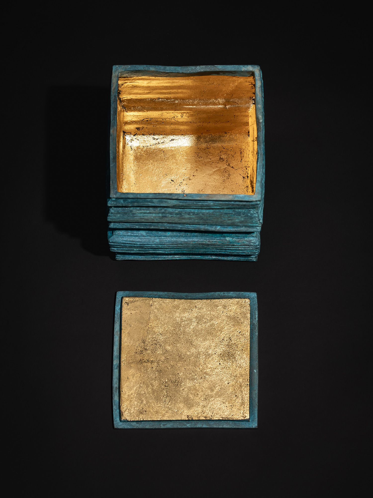 Top-down view of the open Square Strips bronze box with the detached lid shown below, underside...