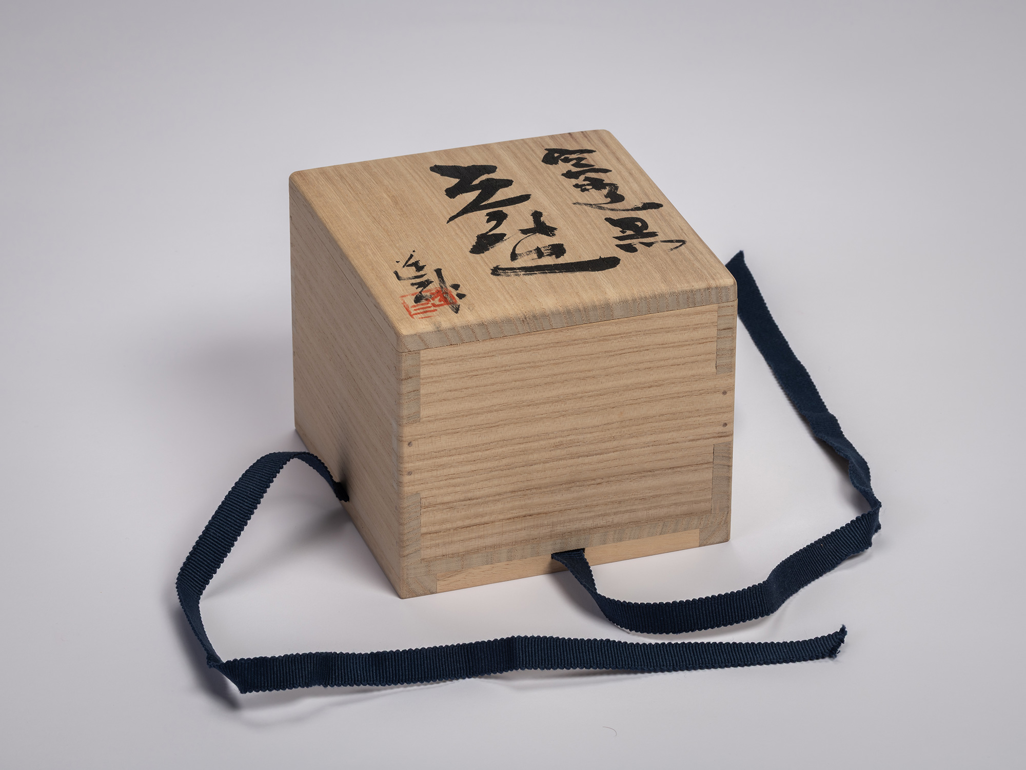 Wooden storage box (tomobako) for Tea Bowl Black by Shōzō Michikawa. The light wood lid features...
