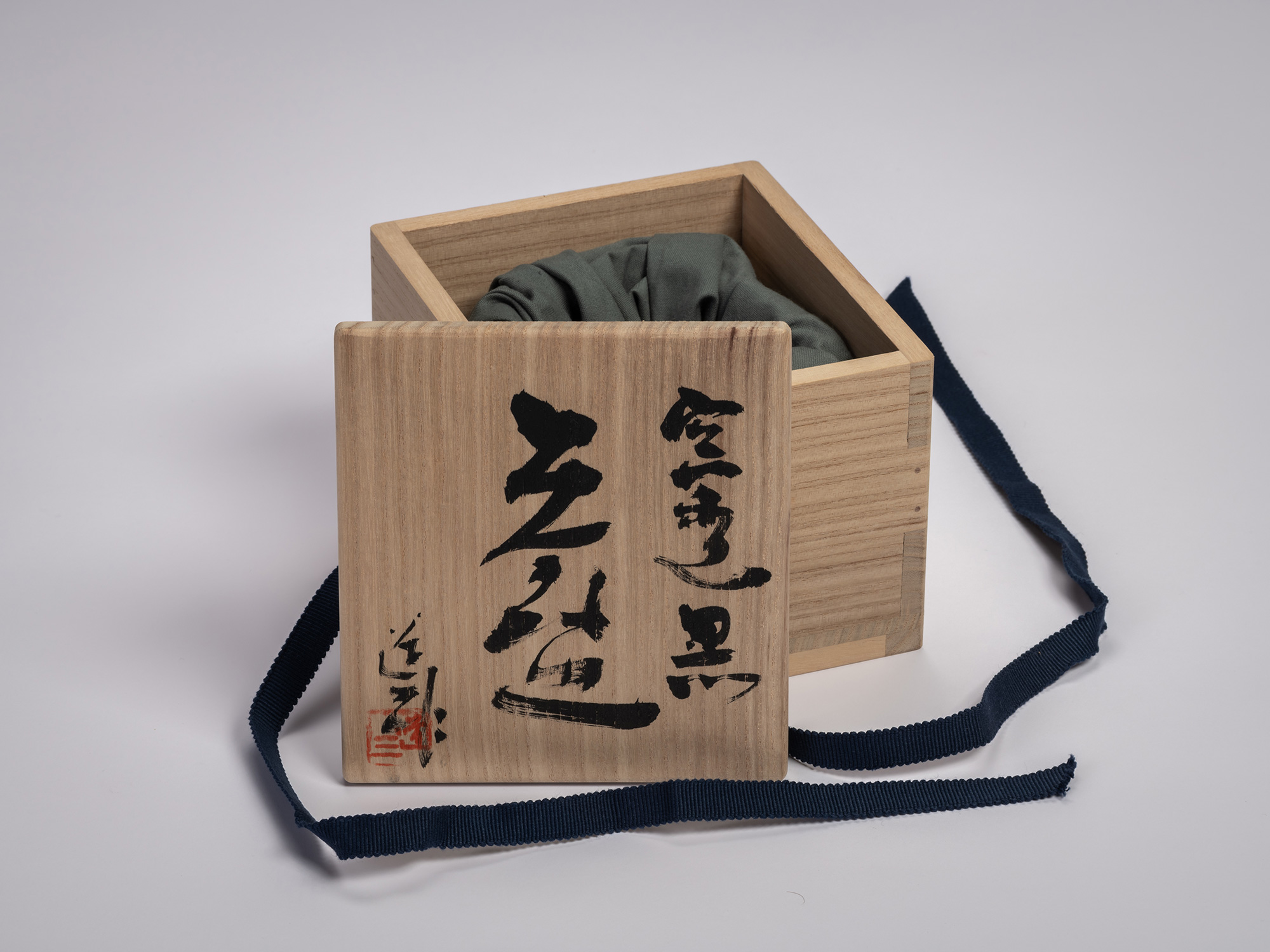 Wooden storage box (tomobako) for Tea Bowl Black by Shōzō Michikawa, shown open with the lid leaning...
