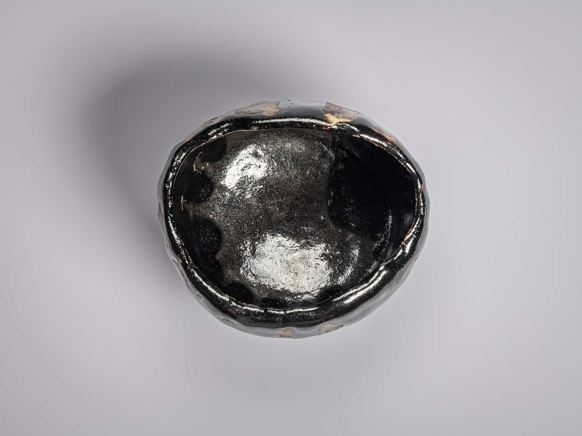 Interior view of Raku XV tea bowl Usokuseki (“Traces of Rain”) featuring a glossy, pooled black...