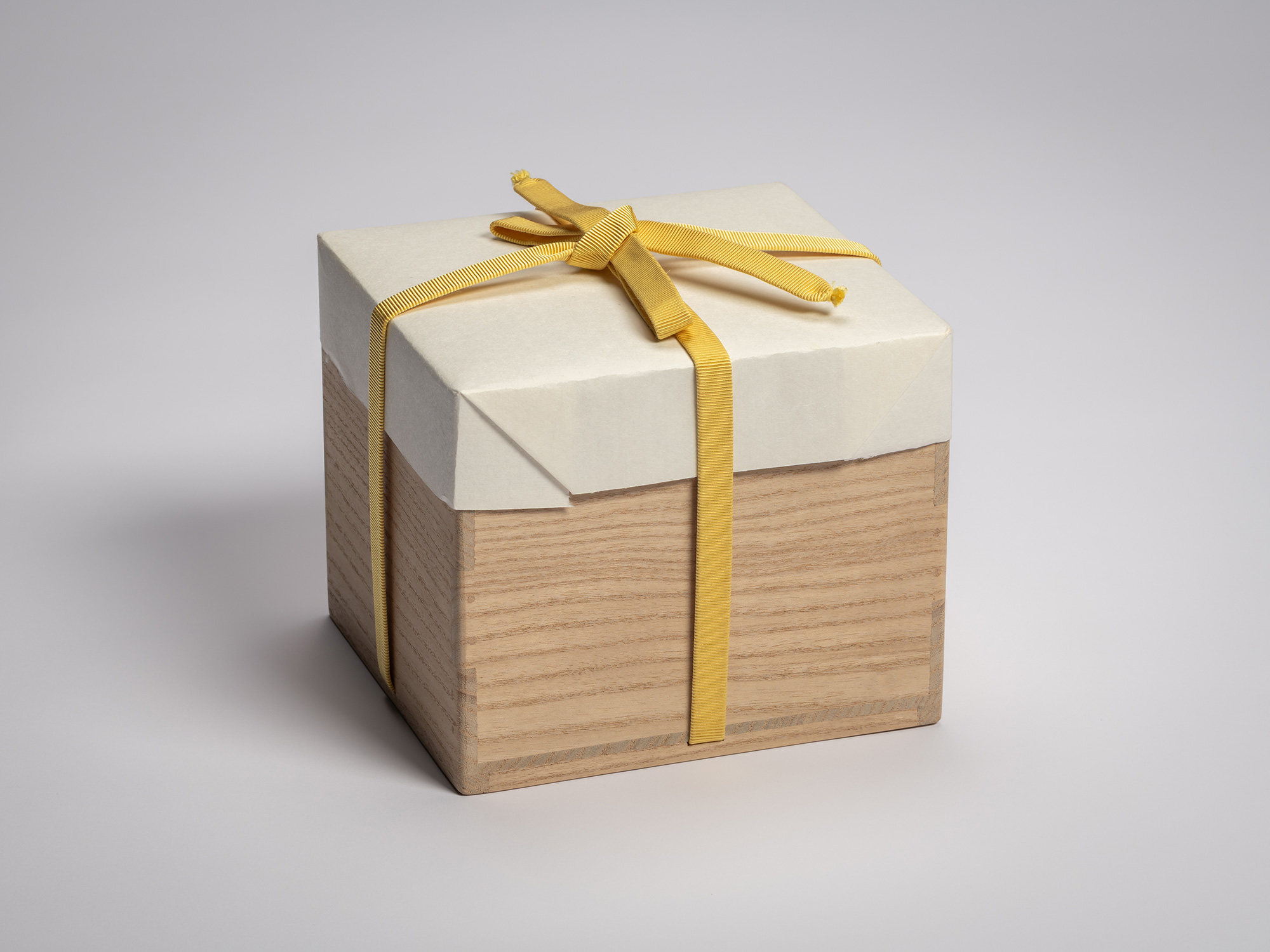 Wooden artist box containing the tea bowl Usokuseki by Raku XV (Jikinyū), tied with a yellow cord...