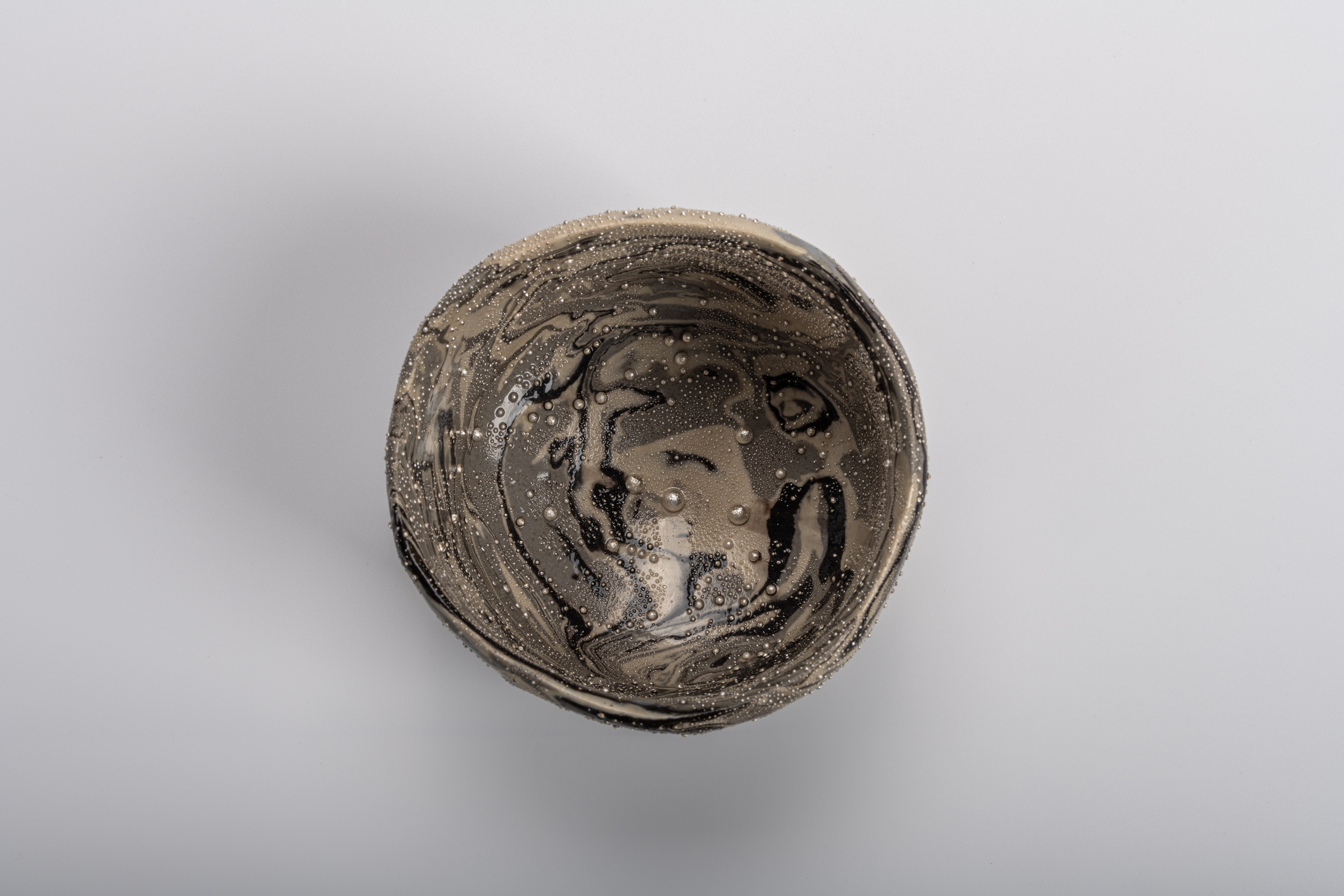 Interior view of Takahiro Kondo’s “Wave Bowl: Tsunami” tea bowl, featuring swirling marbled black,...