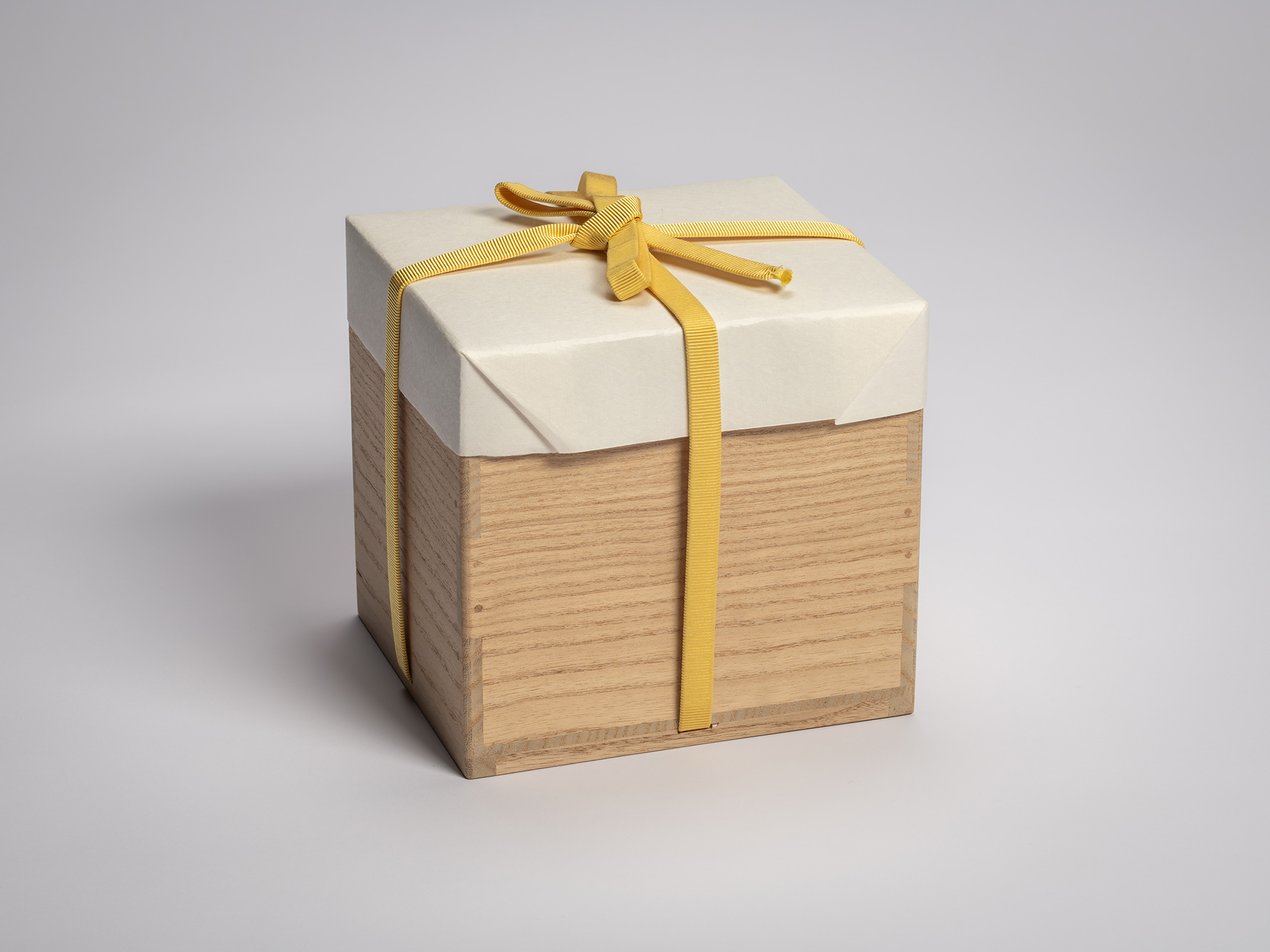 Wooden artist box containing the tea bowl Zan by Raku XV (Jikinyū), tied with a yellow cord and...