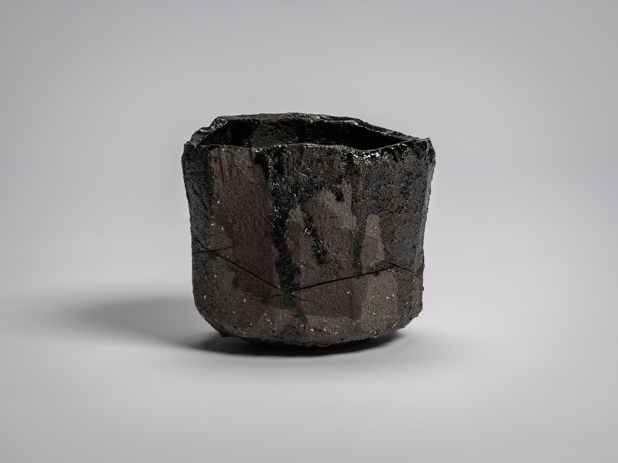 Tea bowl Zan by Raku XV (Jikinyū), featuring a cylindrical, hand-built form with a jagged rim,...