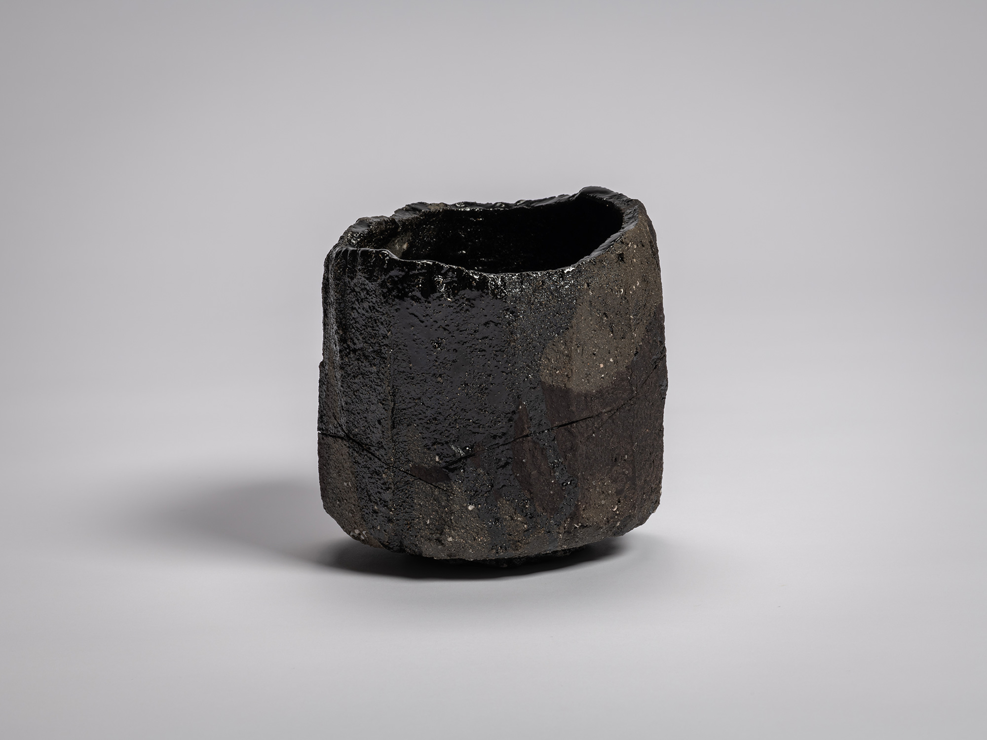 Tea bowl Zan by Raku XV (Jikinyū), featuring a cylindrical, hand-built form with a jagged rim,...