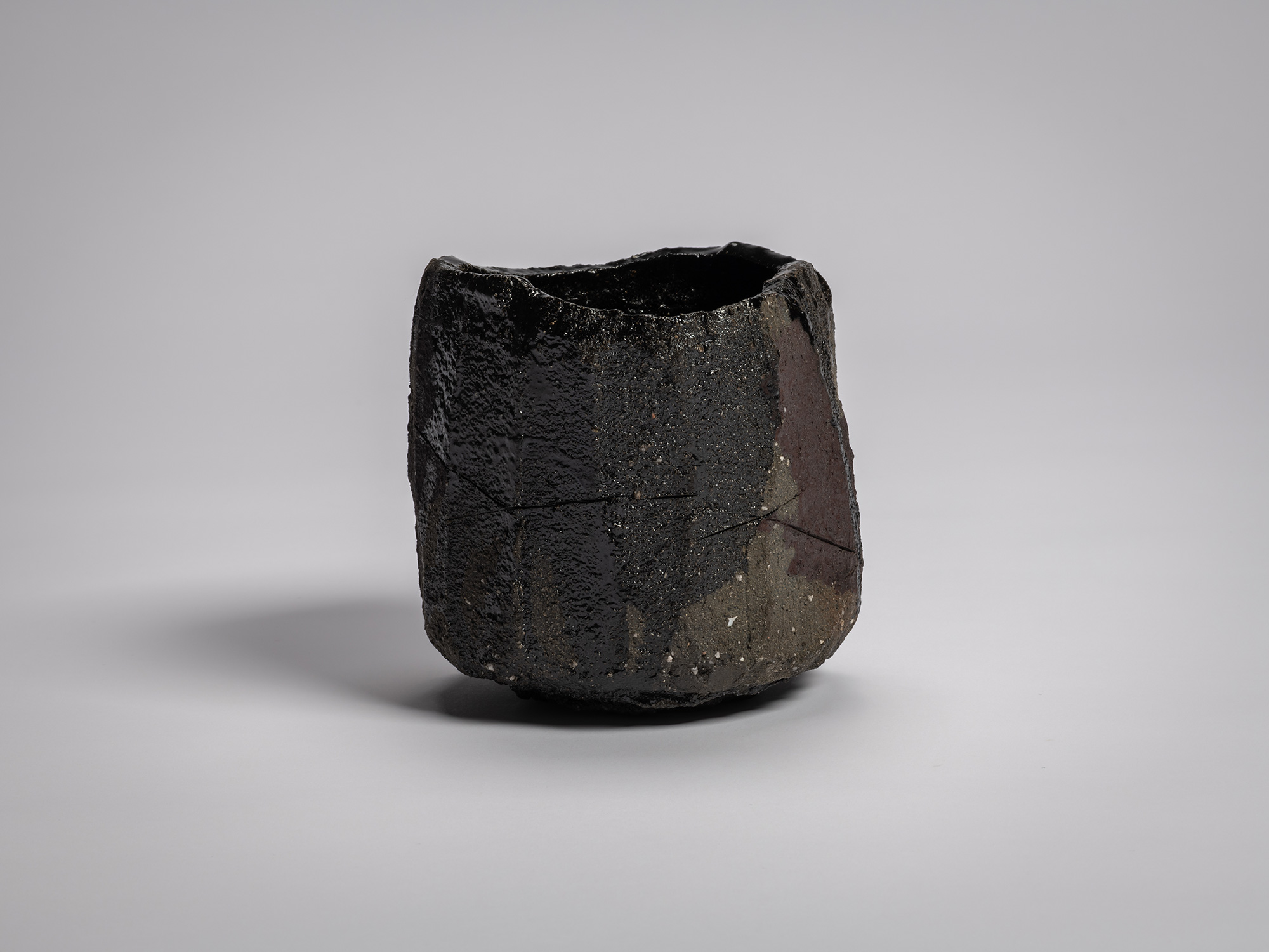Tea bowl Zan by Raku XV (Jikinyū), featuring a cylindrical, hand-built form with a jagged rim,...