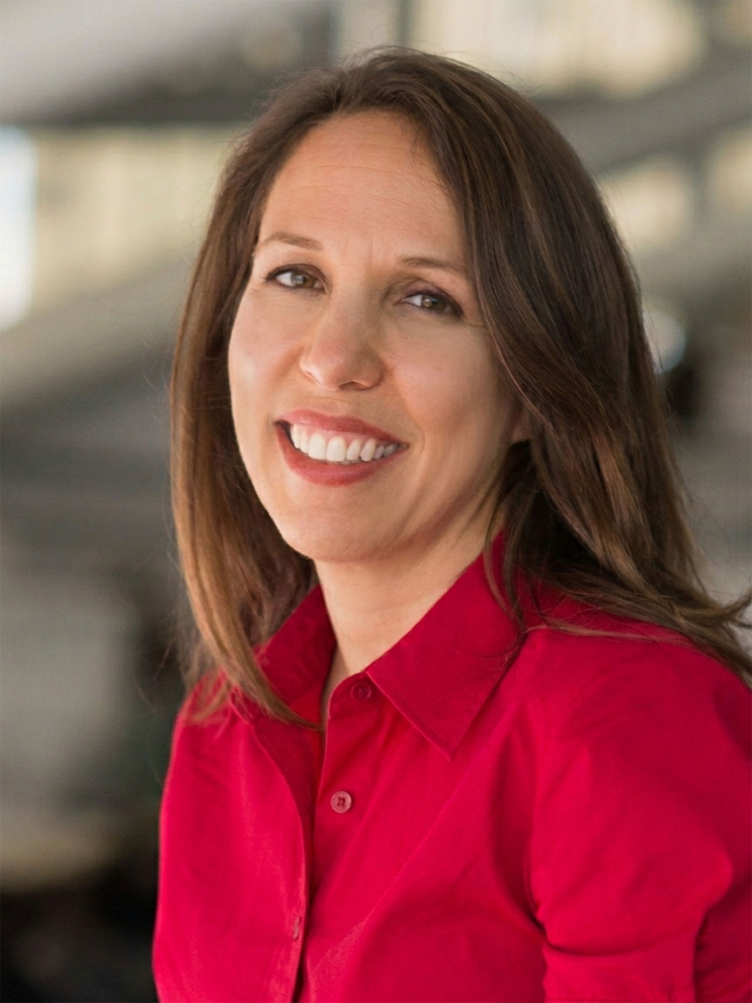 Image of Sarah Bordy, Caucasian female with brown shoulder length hair wearing a red blouse.
