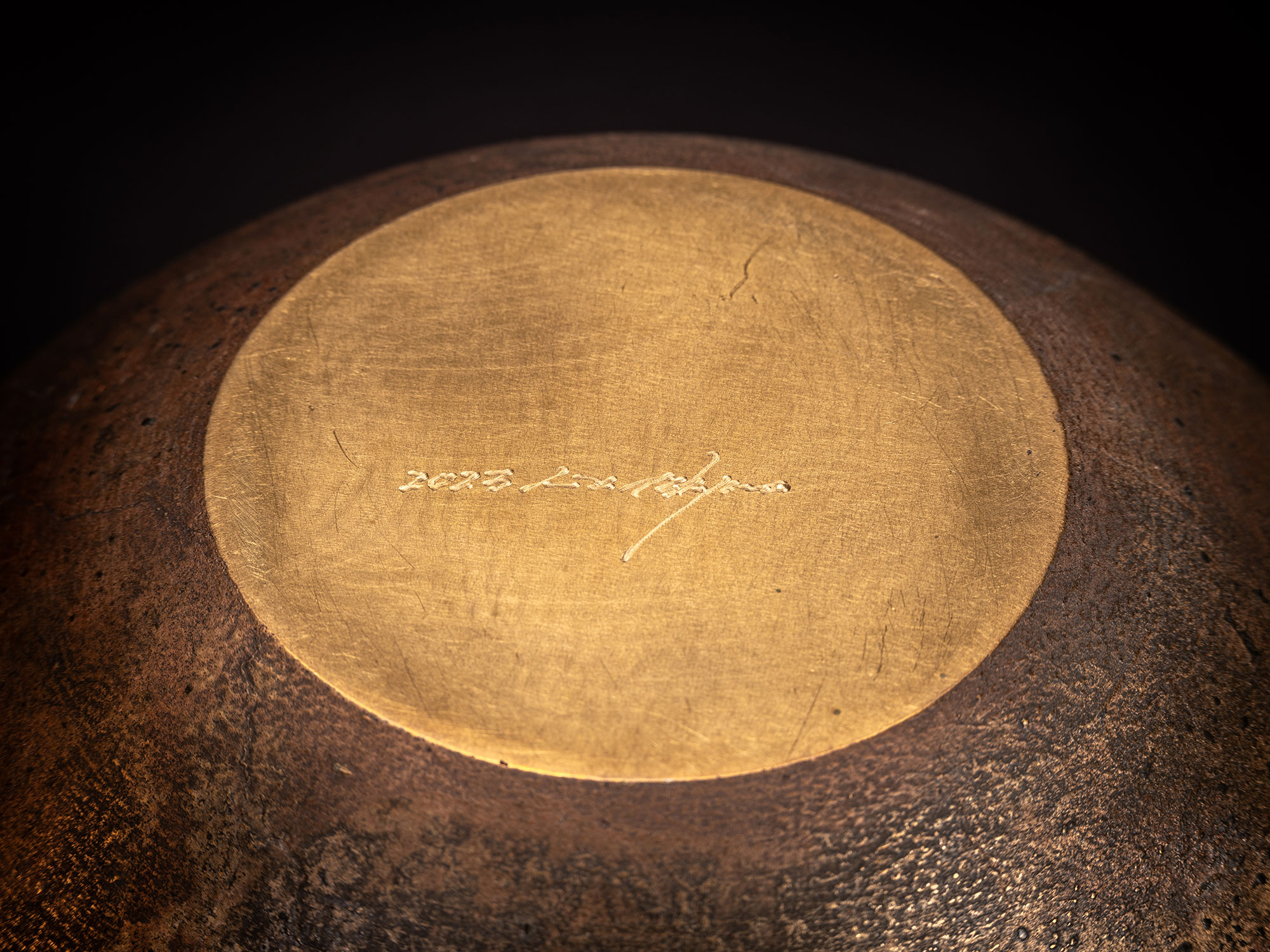 Underside view of a bronze bowl by Koji Hatakeyama showing a circular base with a smooth, polished...