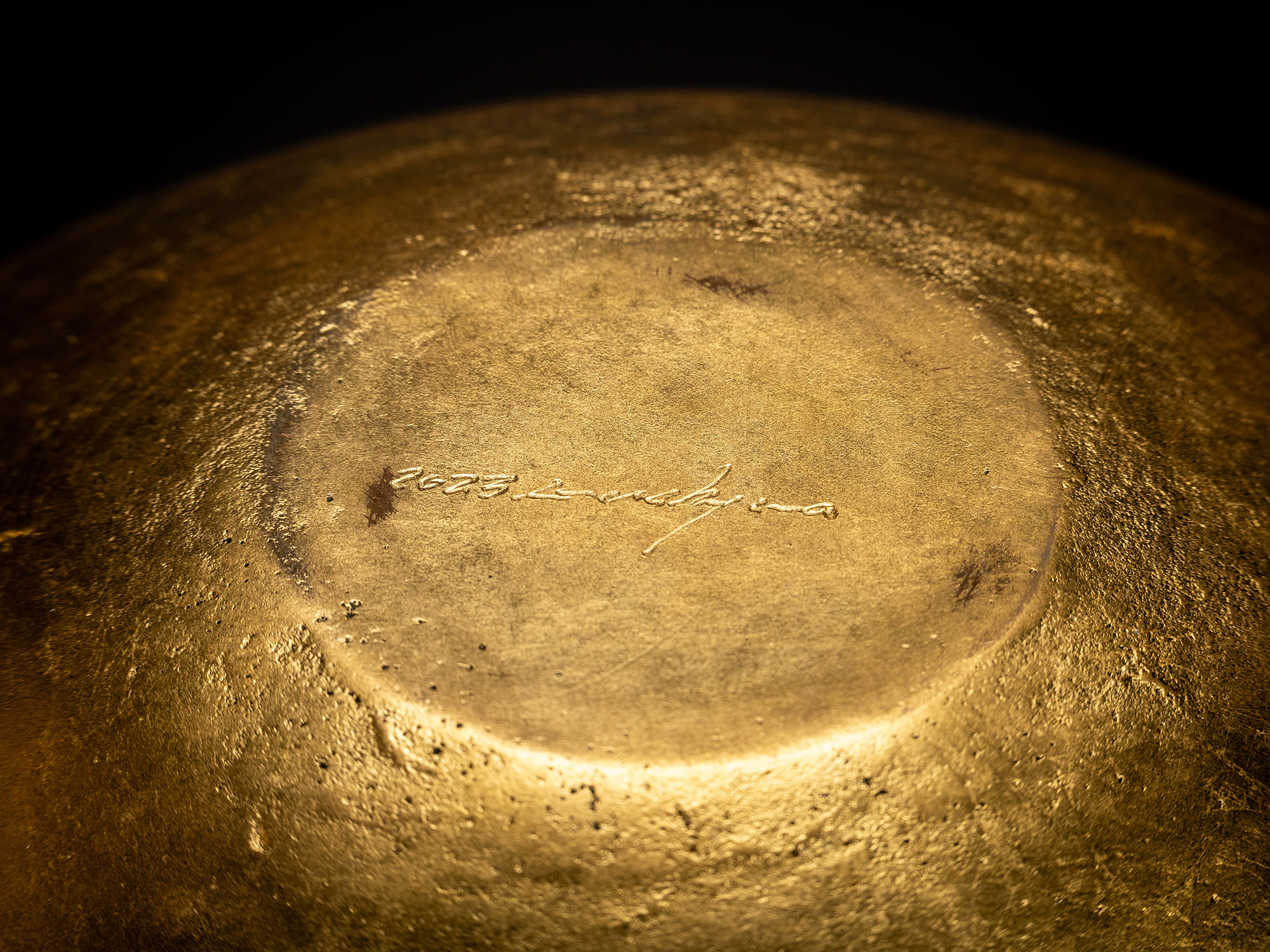 Underside view of a bronze bowl by Koji Hatakeyama showing a circular base with a slightly recessed...