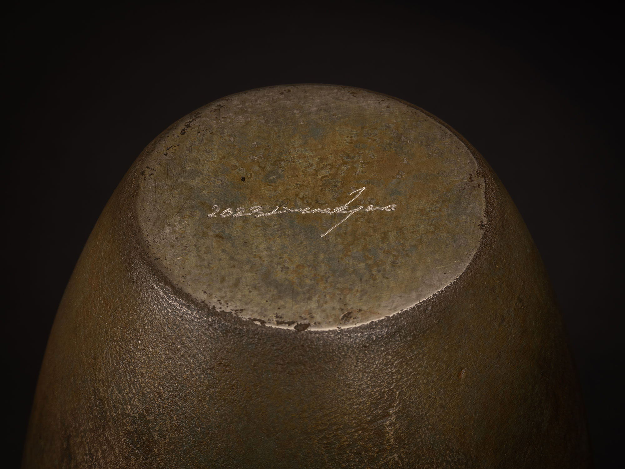Underside view of a bronze vessel by Koji Hatakeyama showing a circular base with a slightly recessed...