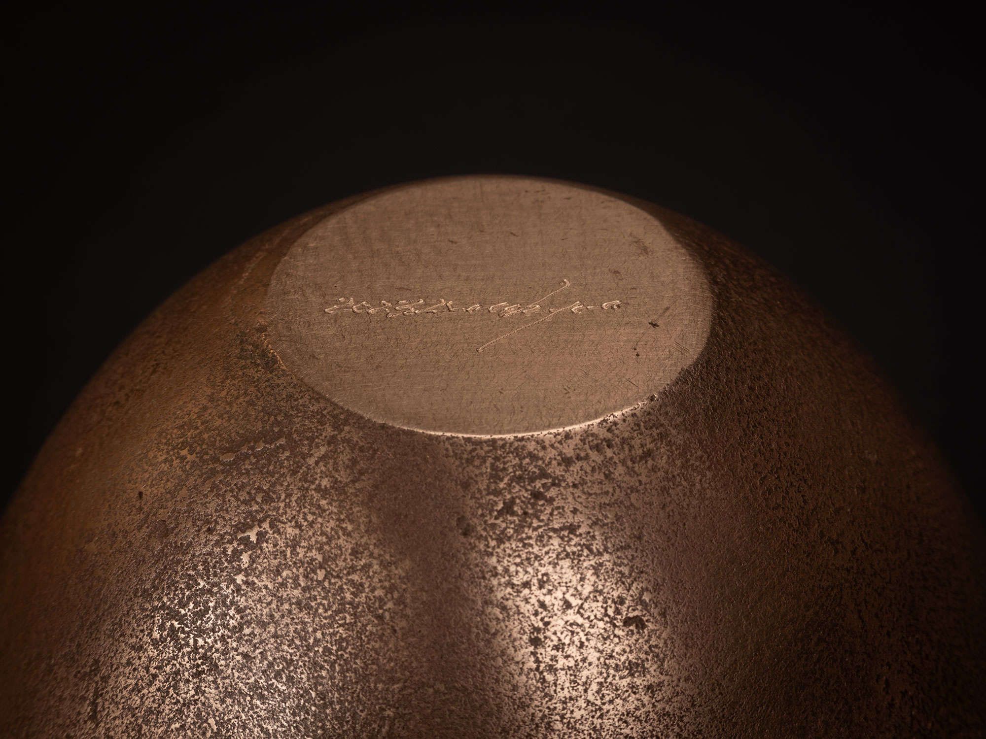 Underside view of a bronze bowl by Koji Hatakeyama showing a circular base with a smooth, slightly...