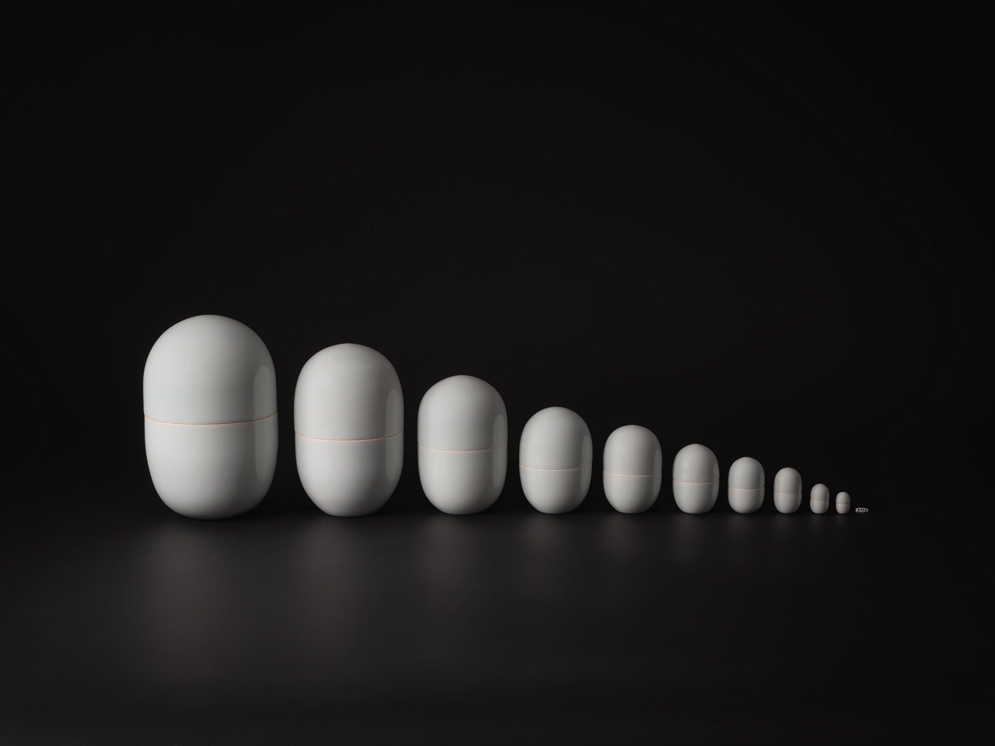 A wide-angle, minimalist photograph of the ceramic work Nesting Covered Boxes by Akira Yagi. The...