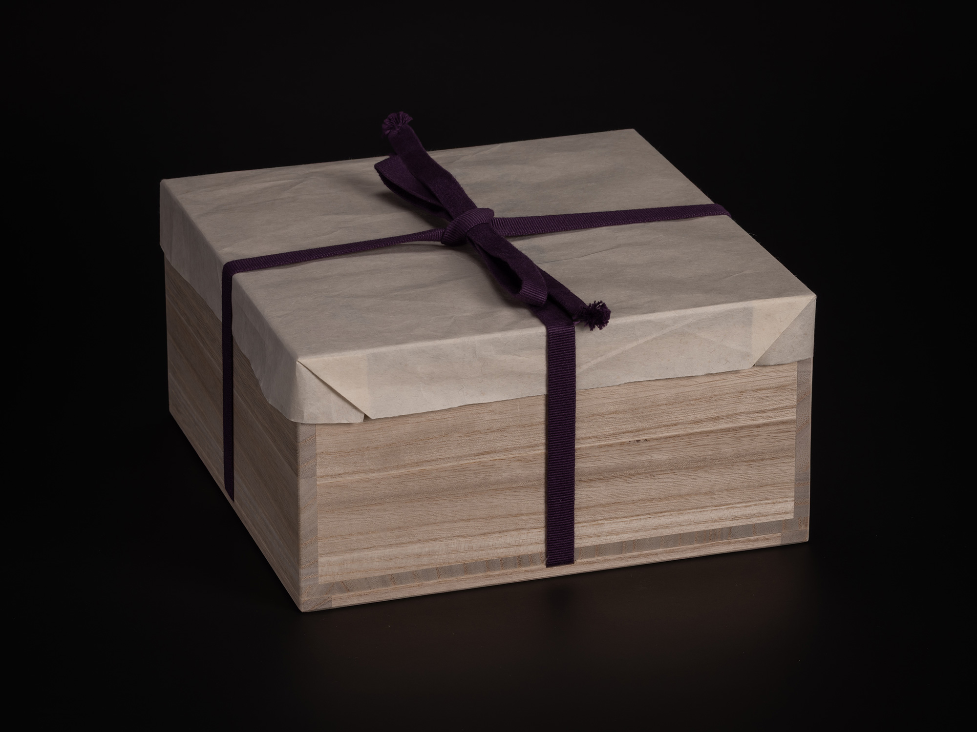 A studio photograph of a traditional Japanese tomobako (wooden storage box) used for the ceramic...