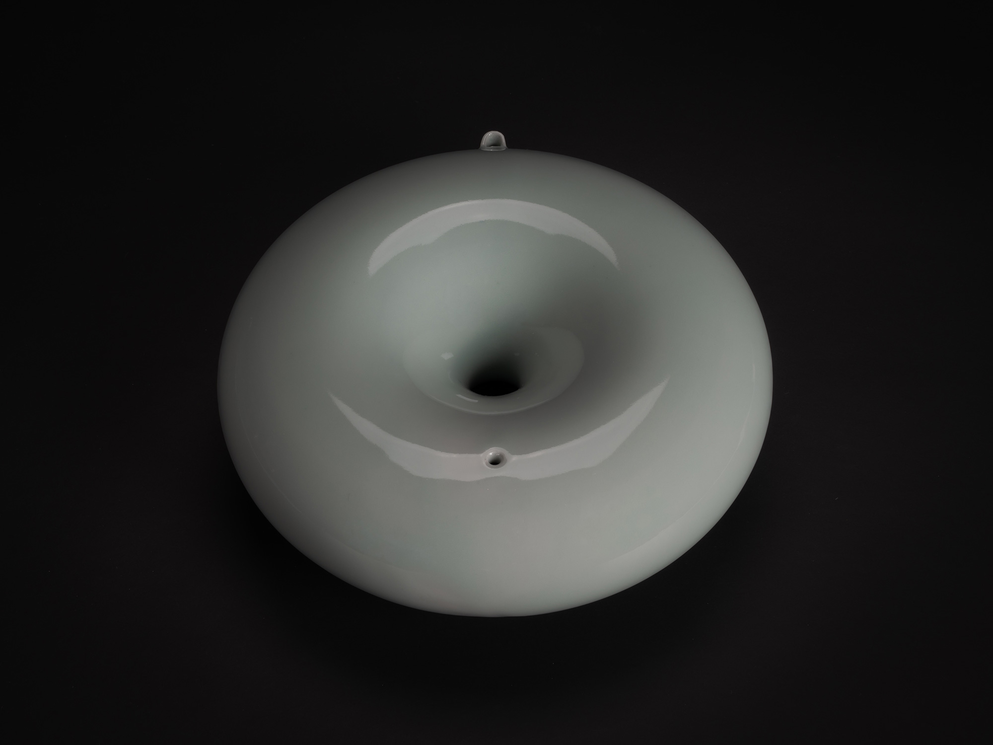 Set against a dark background, a minimalist photograph of a Water Dropper (suiteki) created by...