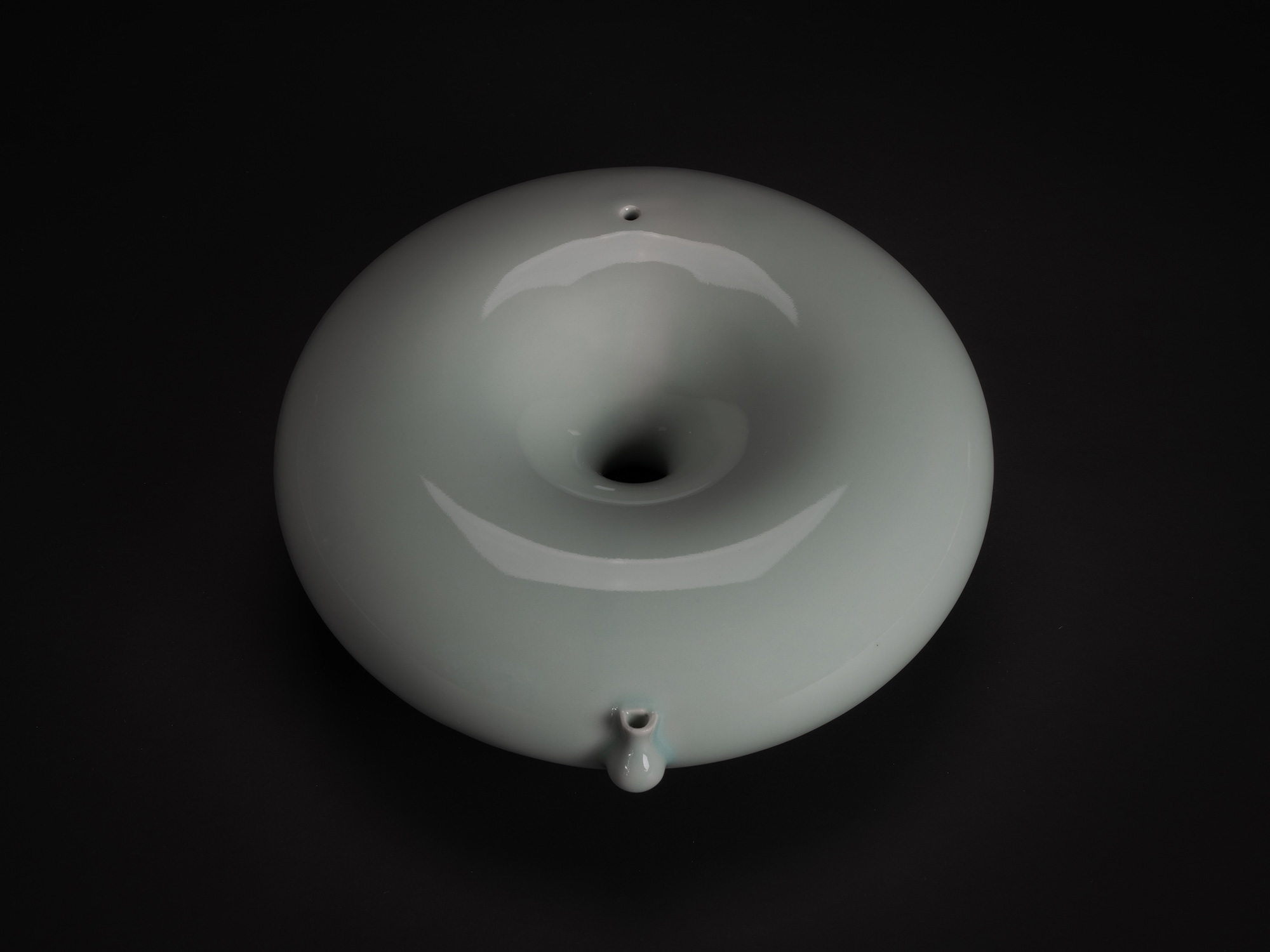 Set against a dark background, a minimalist photograph of a Water Dropper (suiteki) created by...