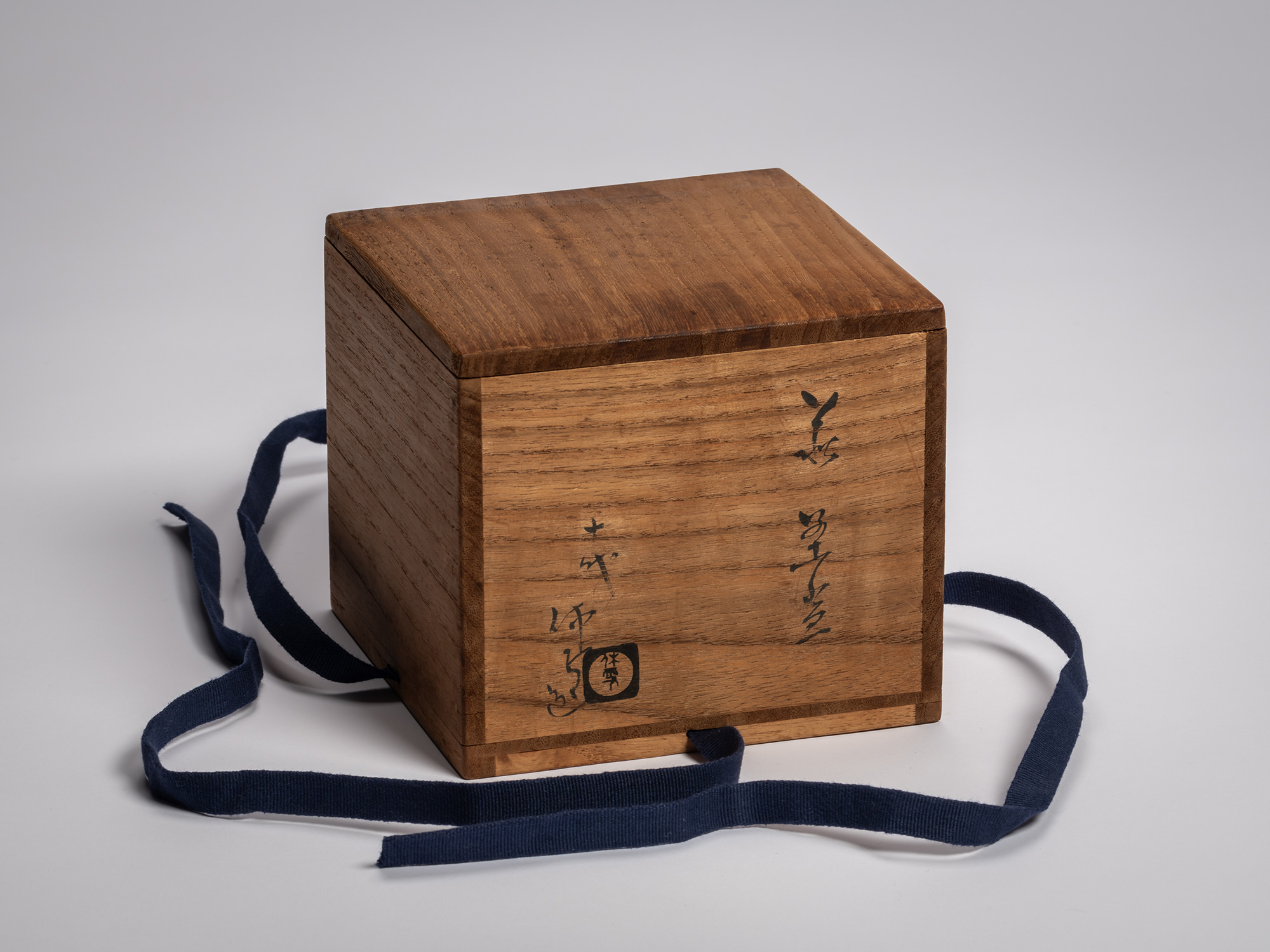 Tomobako (wooden storage box) for a Hagi chawan by Miwa X, shown with the lid removed and a dark...